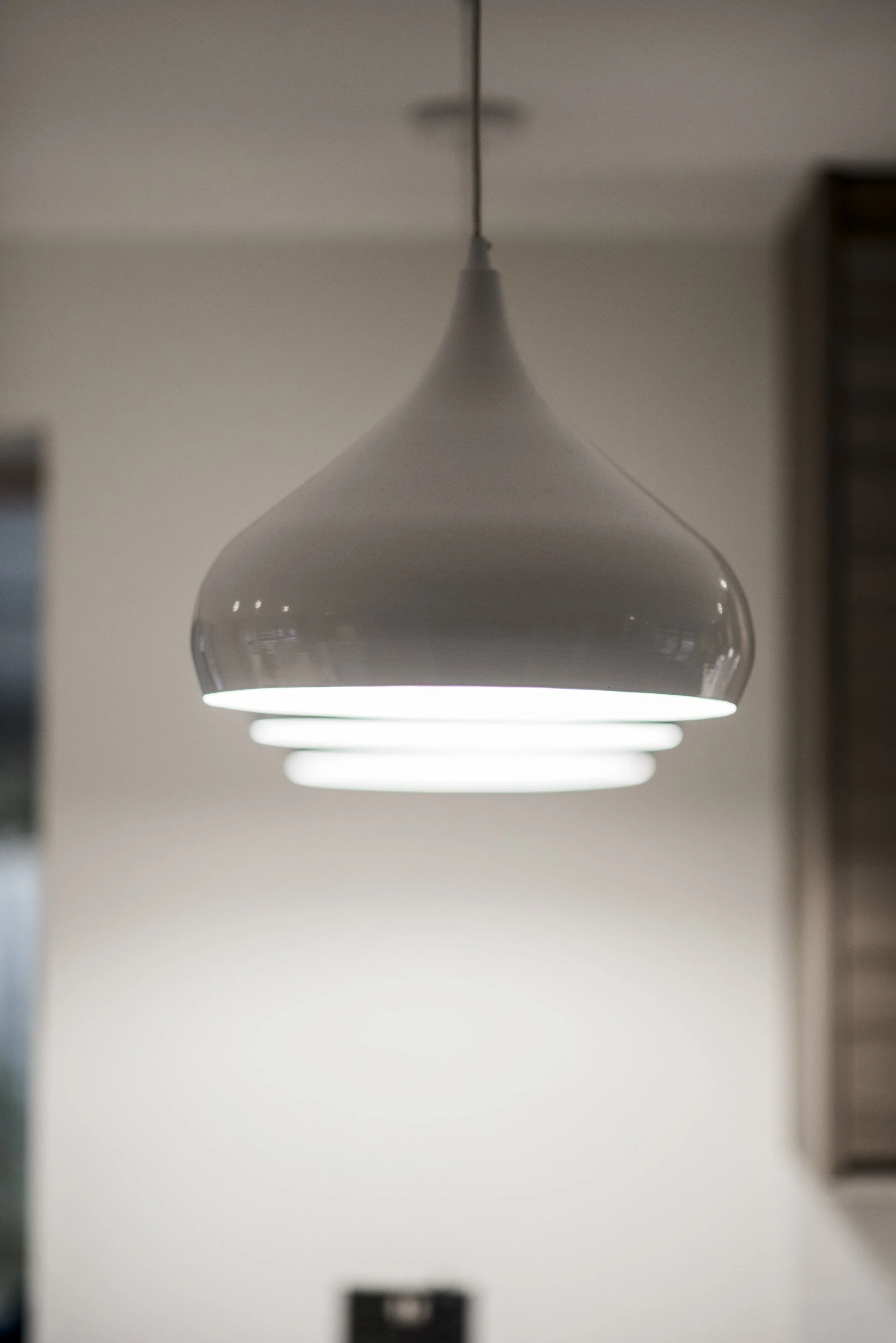 Modern white pendant light hanging from a ceiling in a room.
