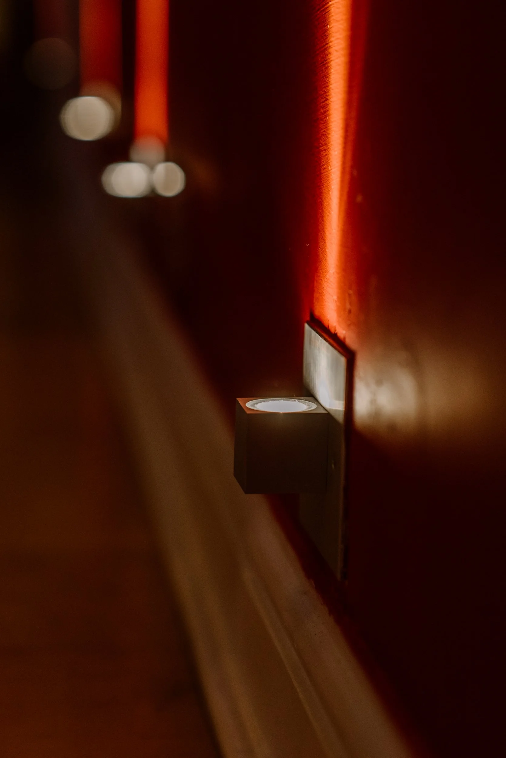 Close-up of a wall-mounted light fixture illuminating a red wall with a warm glow.