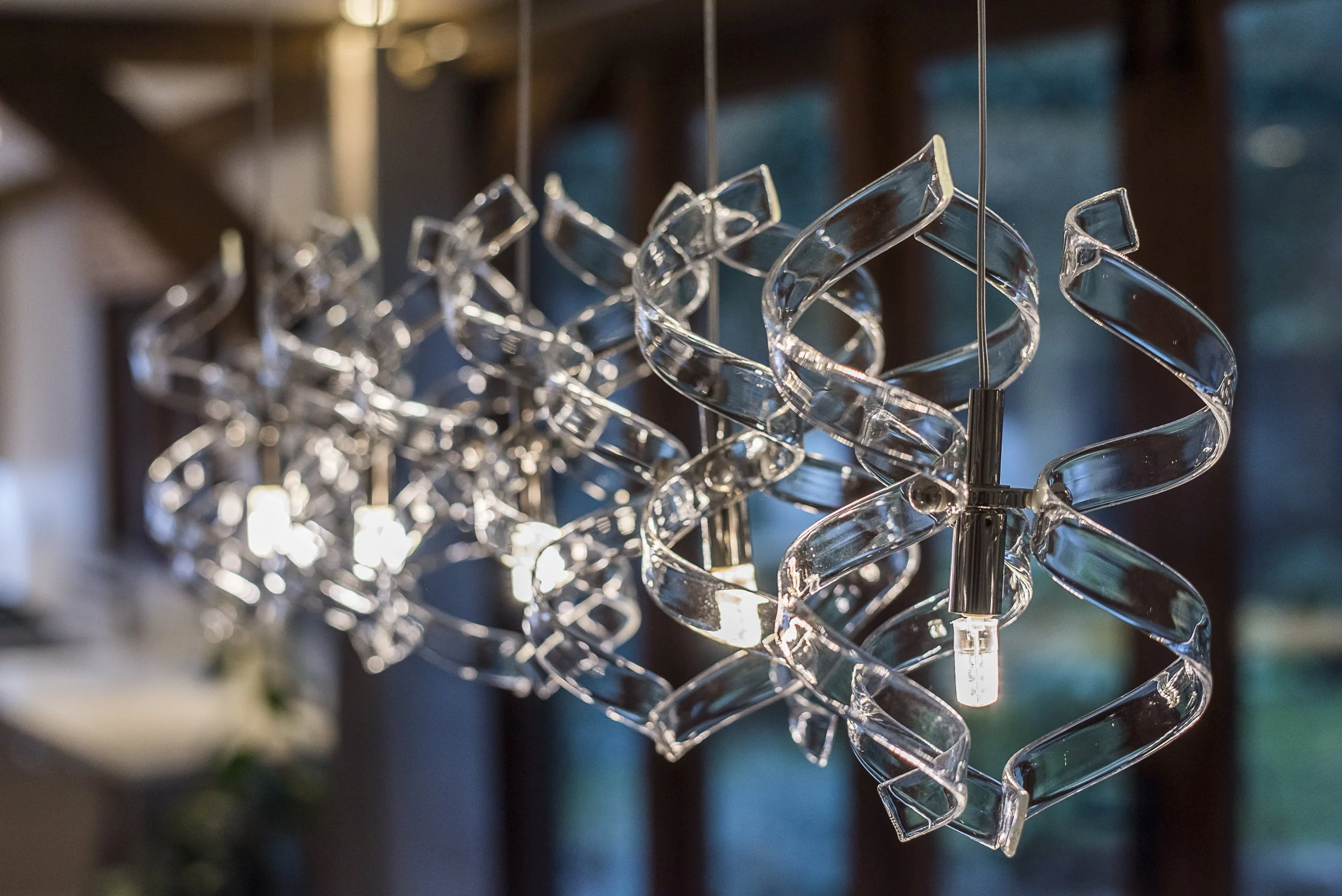 Close-up of a modern chandelier with intertwined glass spirals and LED bulbs.