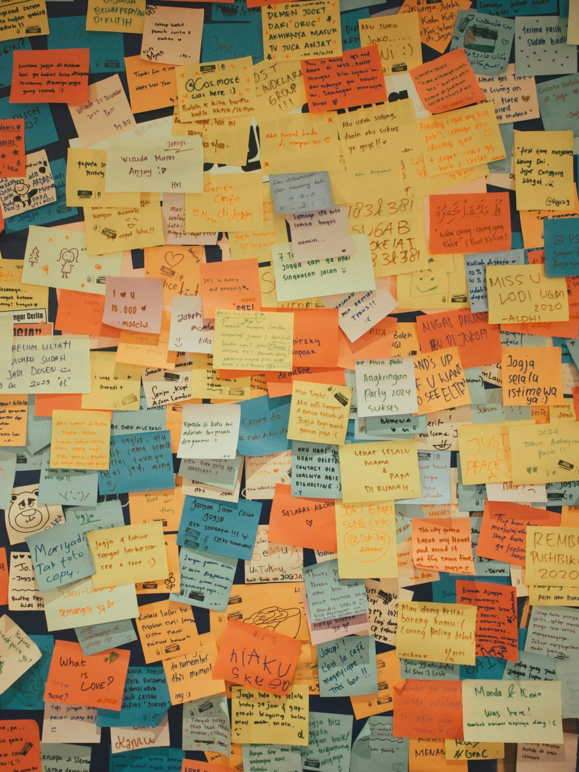 A collage of colorful sticky notes and pieces of paper with handwritten messages, doodles, and drawings in various colors including yellow, orange, blue, green, and white.