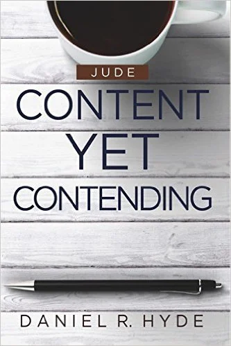 Book cover titled "Content Yet Contending" by Daniel R. Hyde, featuring a white mug filled with dark coffee at the top, set on a white wooden surface, with a black pen at the bottom.