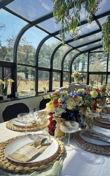 Rustic elegant baby shower tablescape with purple and mixed floral arrangements, chair covers and vintage glassware down long table with gold accents and natural light in sunroom Central NJ Monmouth County - CelebrationShare