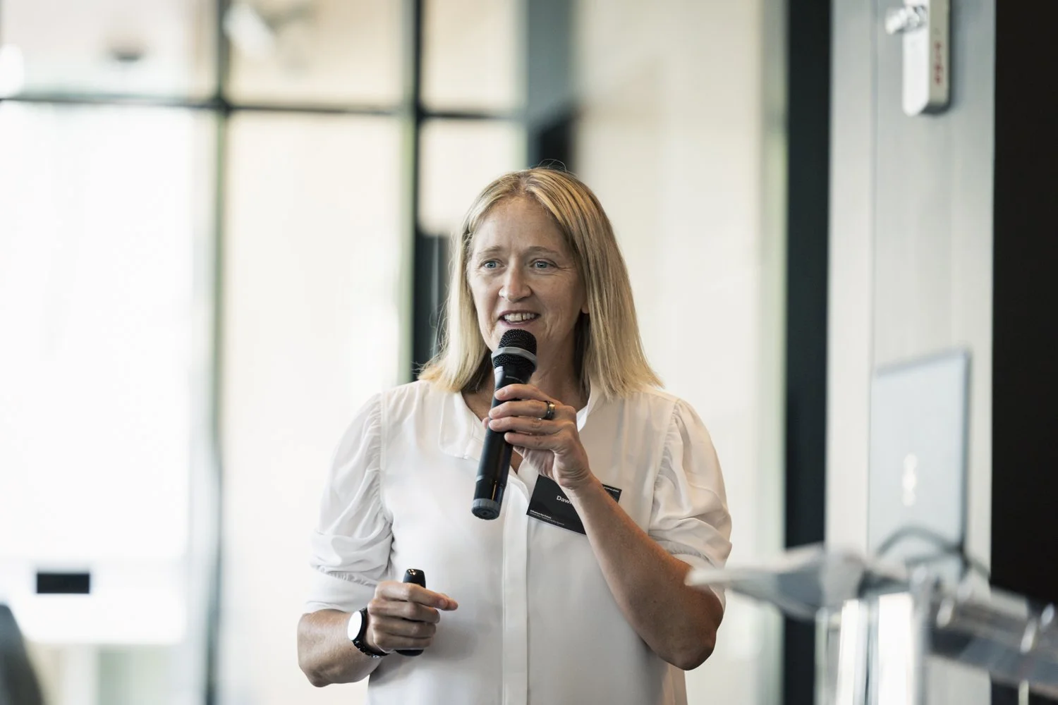 Dawn Scott giving a presentation while holding a microphone indoors.