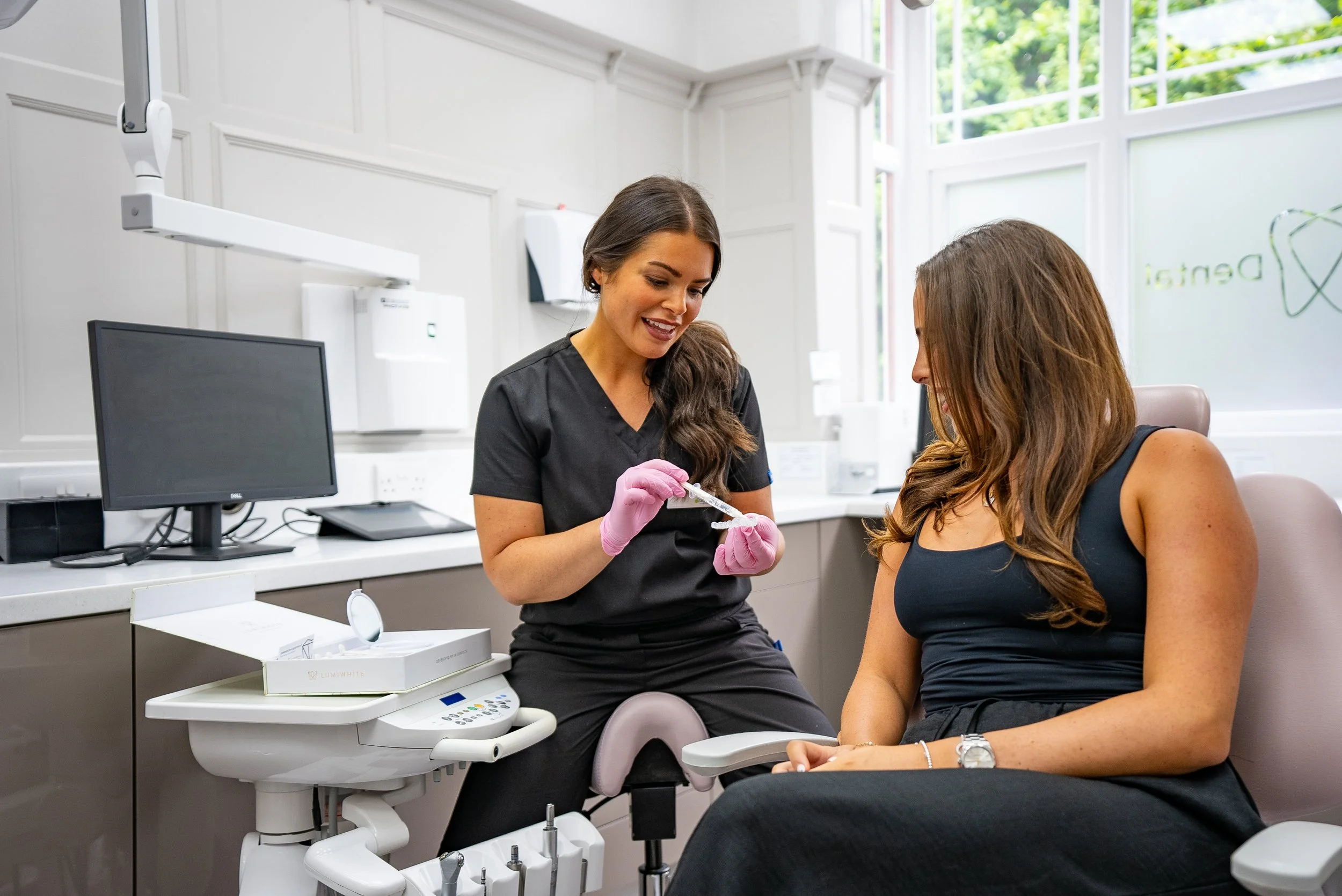 A healthcare professional preparing a syringe with a patient sitting in a dental clinic chair.