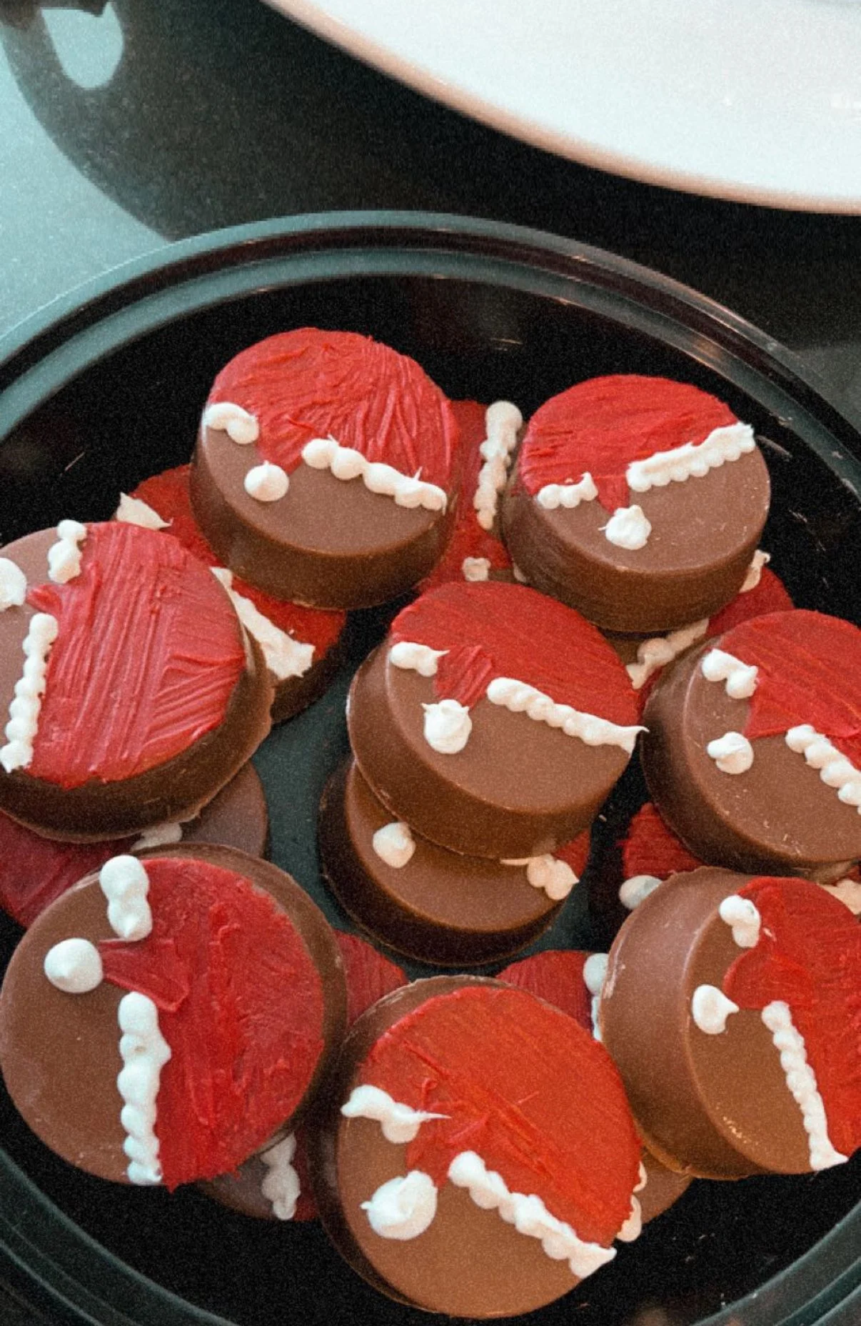 A tray of mini chocolates decorated with red and white icing, resembling Santa hats.