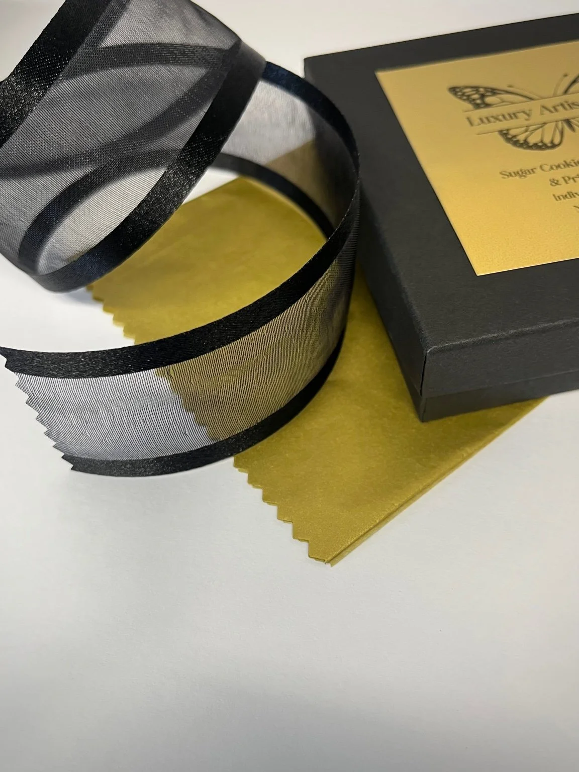 Luxury printed cookie packaging with branded box and ribbon, shown as part of the Luxury Artisan Gifts contact page.