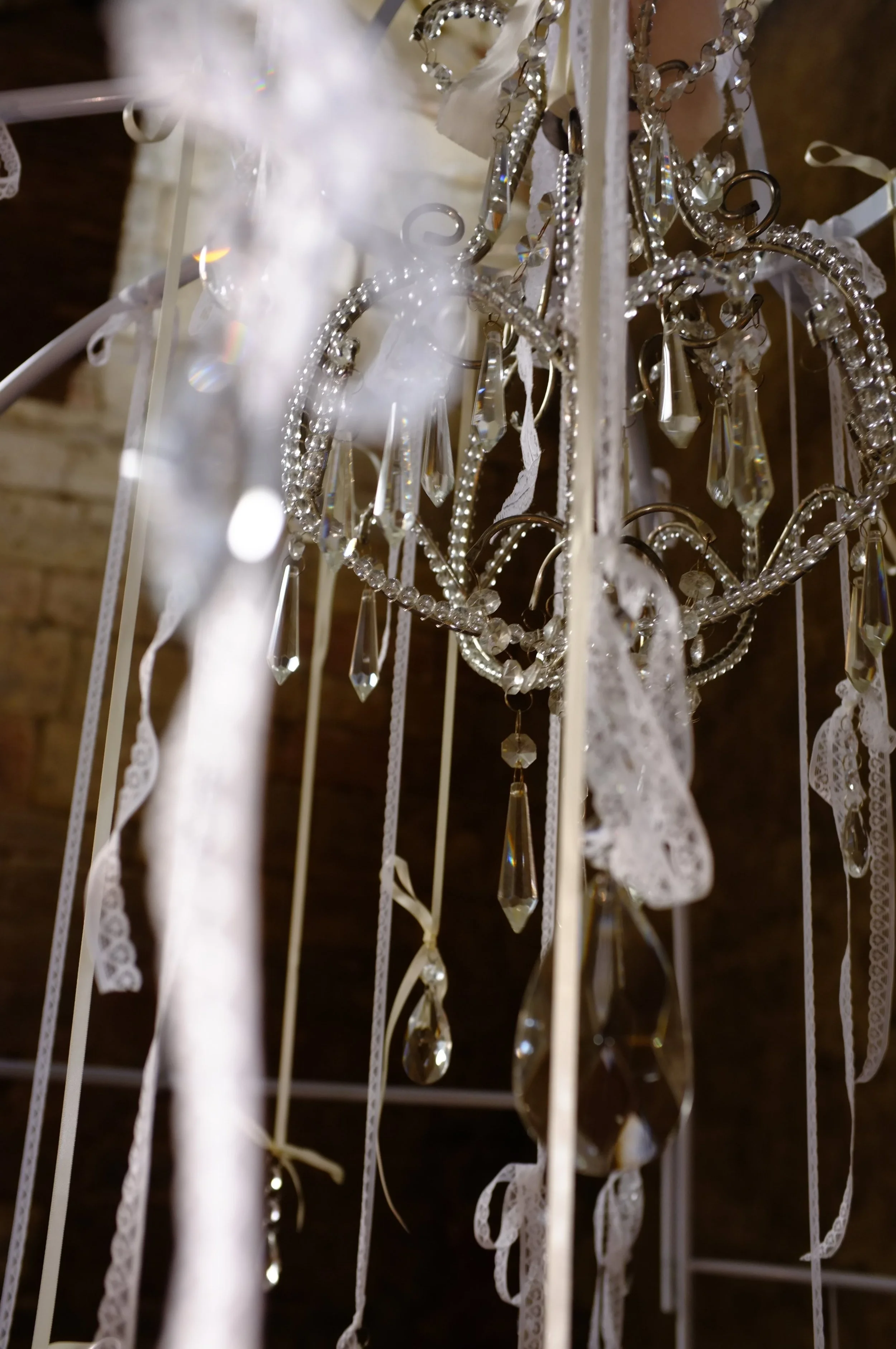 Statement antique chandelier with lace ribbons forming a distinctive and artistic vintage wedding feature
