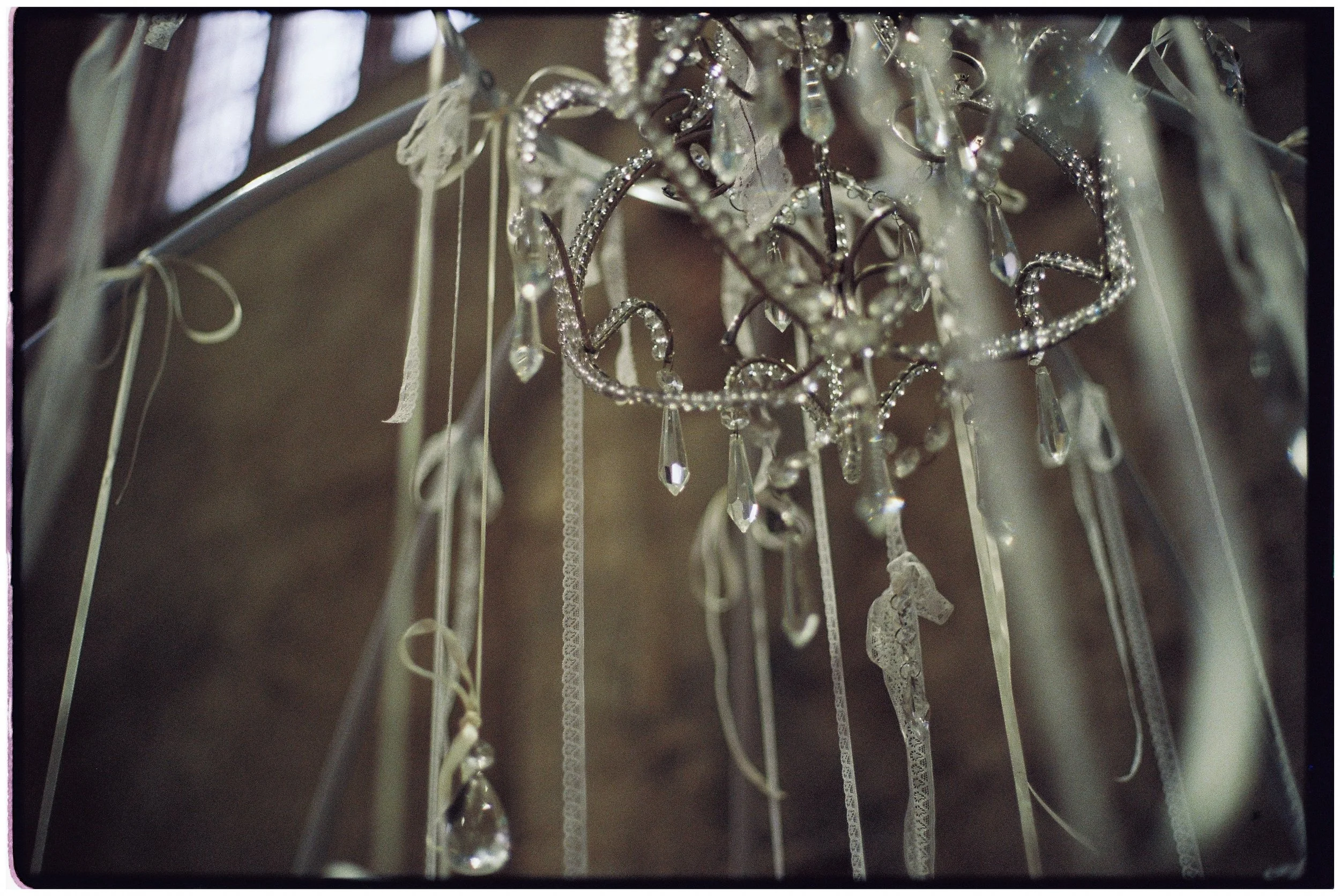 Antique chandelier decorated with trailing lace ribbons for a Victorian-inspired London wedding