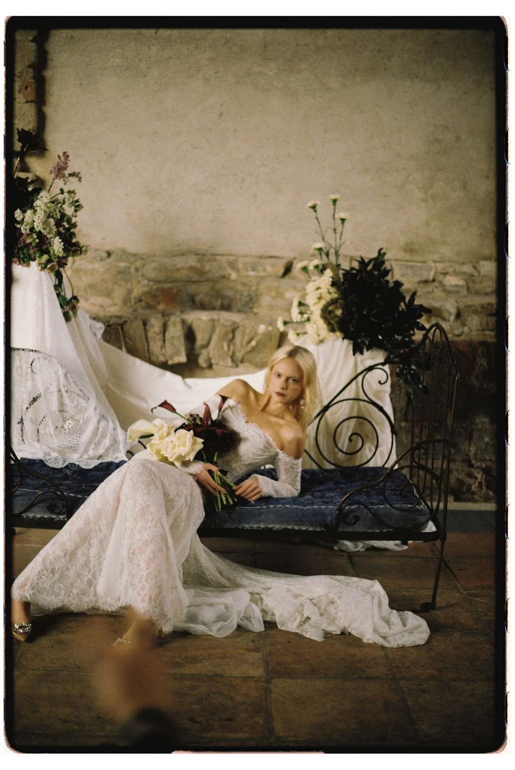 Bridal portrait in luxury wedding gown framed by a flowing draped backdrop and delicate florals