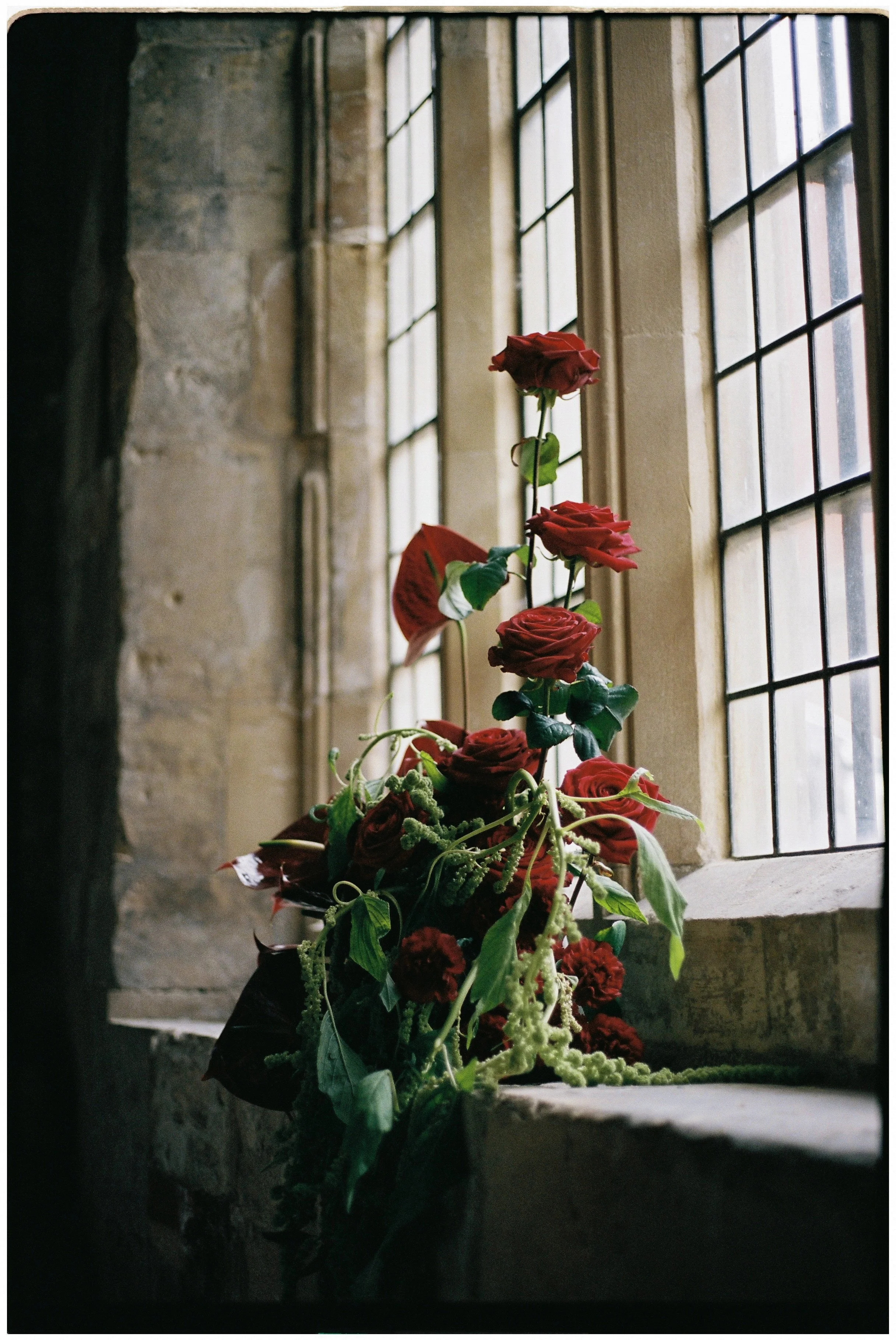 Dramatic wedding flowers in shades of pink, burgundy and red with trailing foliage