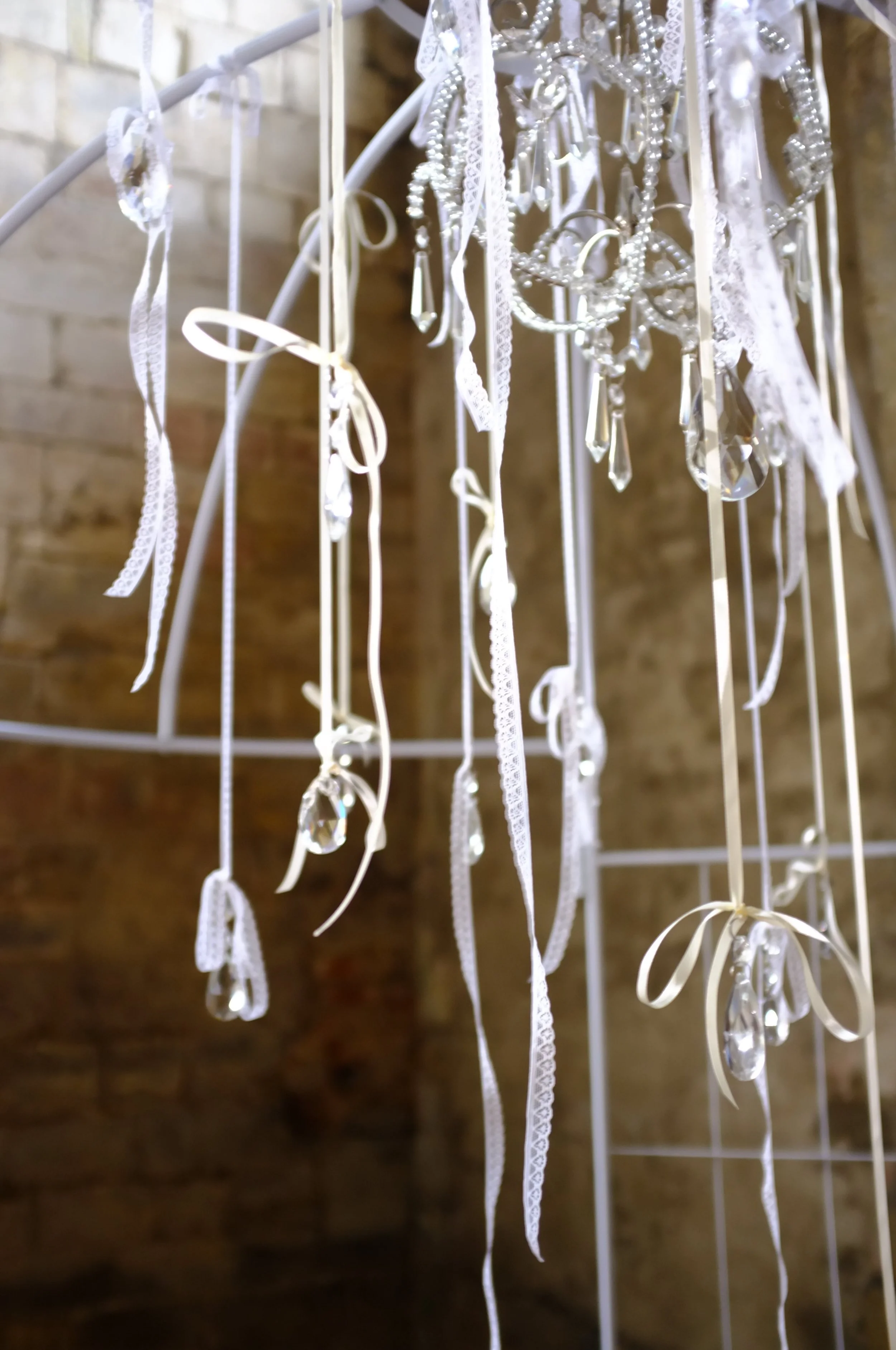Unique wedding installation featuring an antique chandelier with flowing lace and ribbon styling