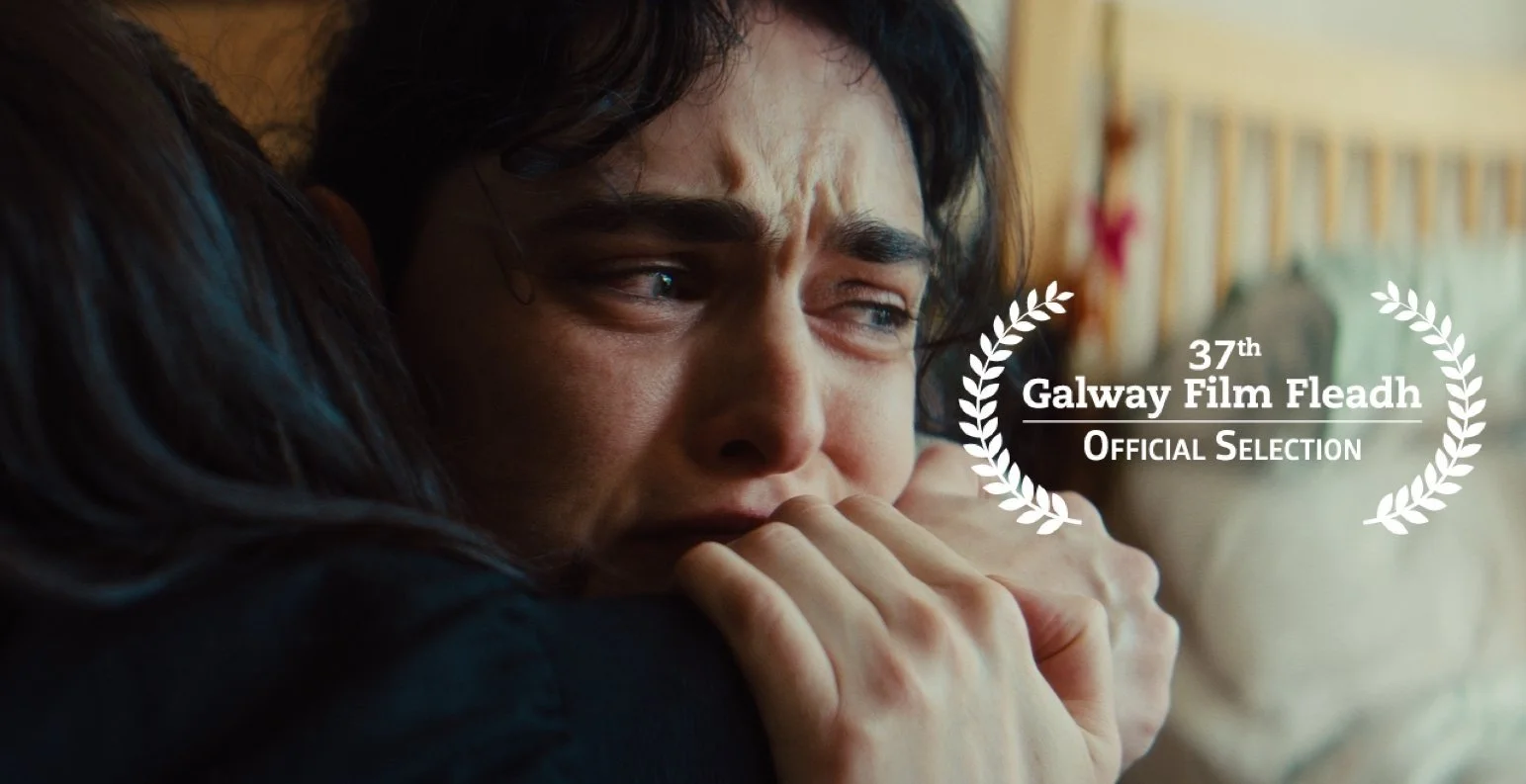 A woman with dark hair appears emotional, hugging someone, with tears in her eyes. There is a text overlay that reads '37th Galway Film Fleadh Official Selection' with laurel wreaths on either side.