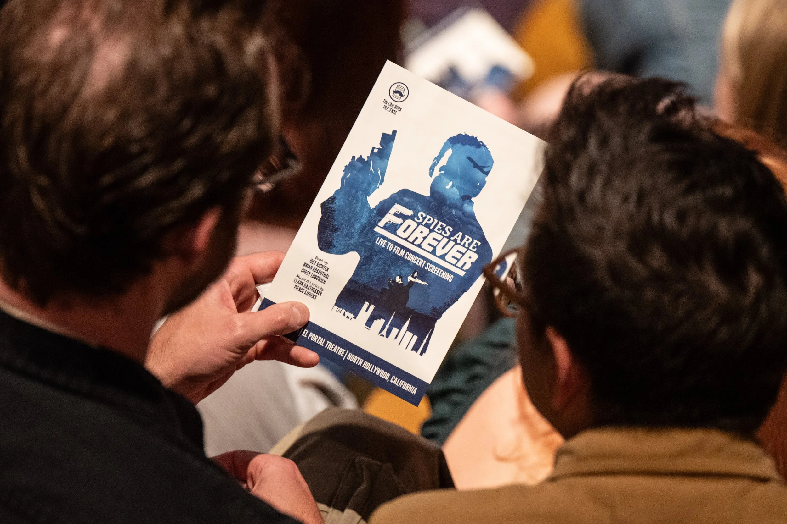 a playbill for Brian, owner of Make The Damn Show, Spies are Forever prouction he produced and starred in. the program is blue and white and held by a hand