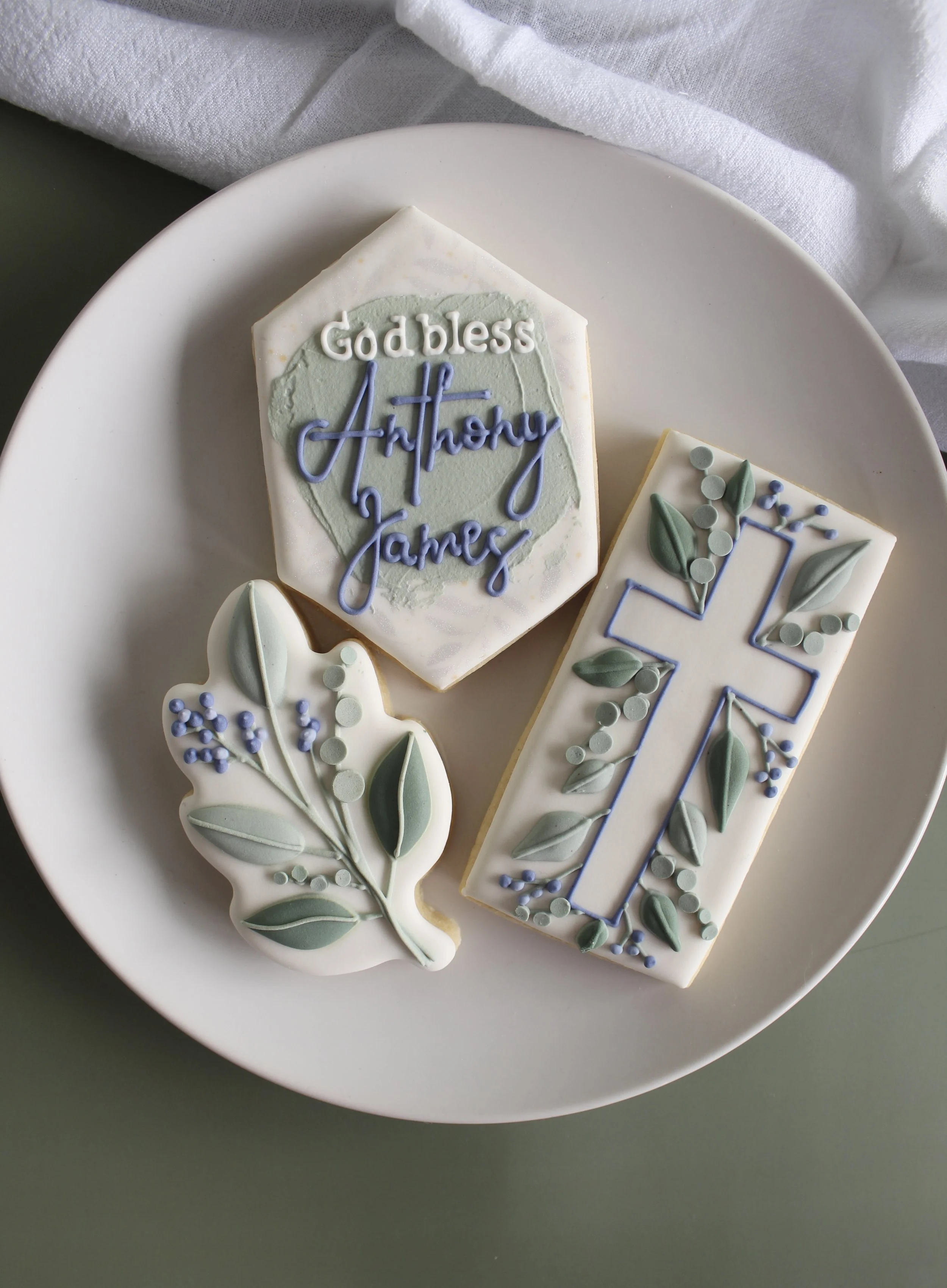 Decorated religious cookies featuring crosses and leaves on a clear tray.
