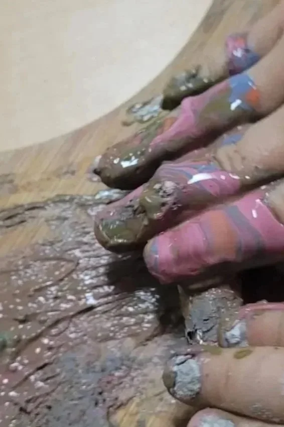 Child's hands working with clay. Messy fingers on a wooden cutting board. Sensory play.