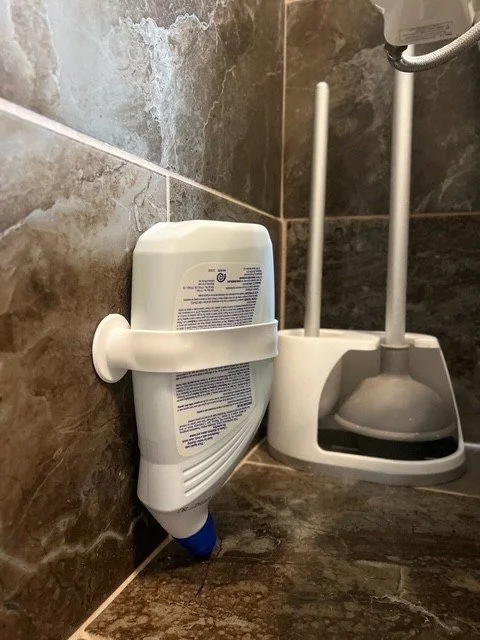 Colorful silicone bottle stabilizers with suction cups and water droplets, placed on a soapy surface. Bath and shower product organization. Zero waste, save money. Every last drop. Lick it, Stick it and Flip it.