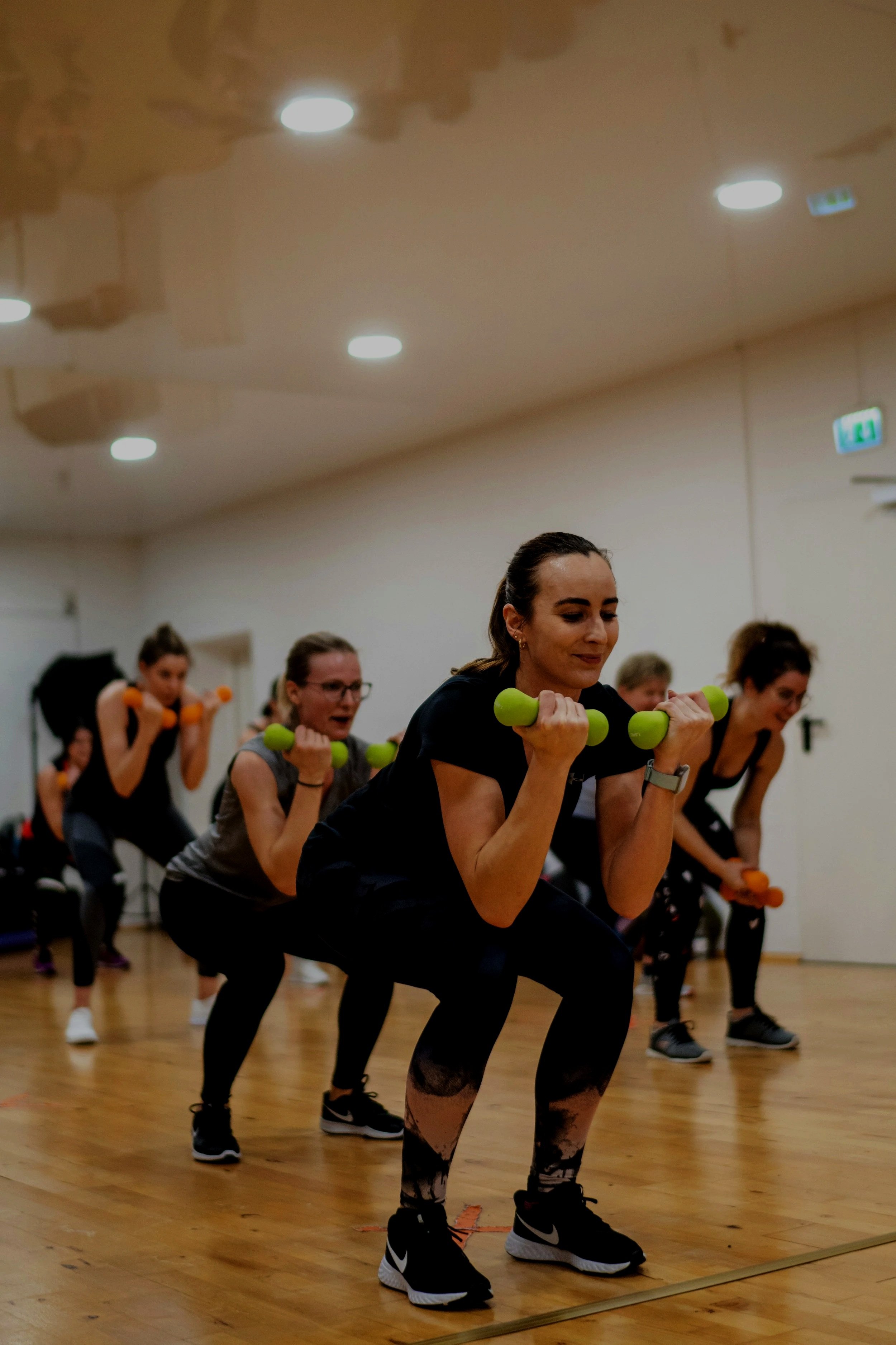 A smiling man at a checkout counter faces a woman with curly hair that is purchasing from a retail shop. He is providing excellent customer service support to the client.