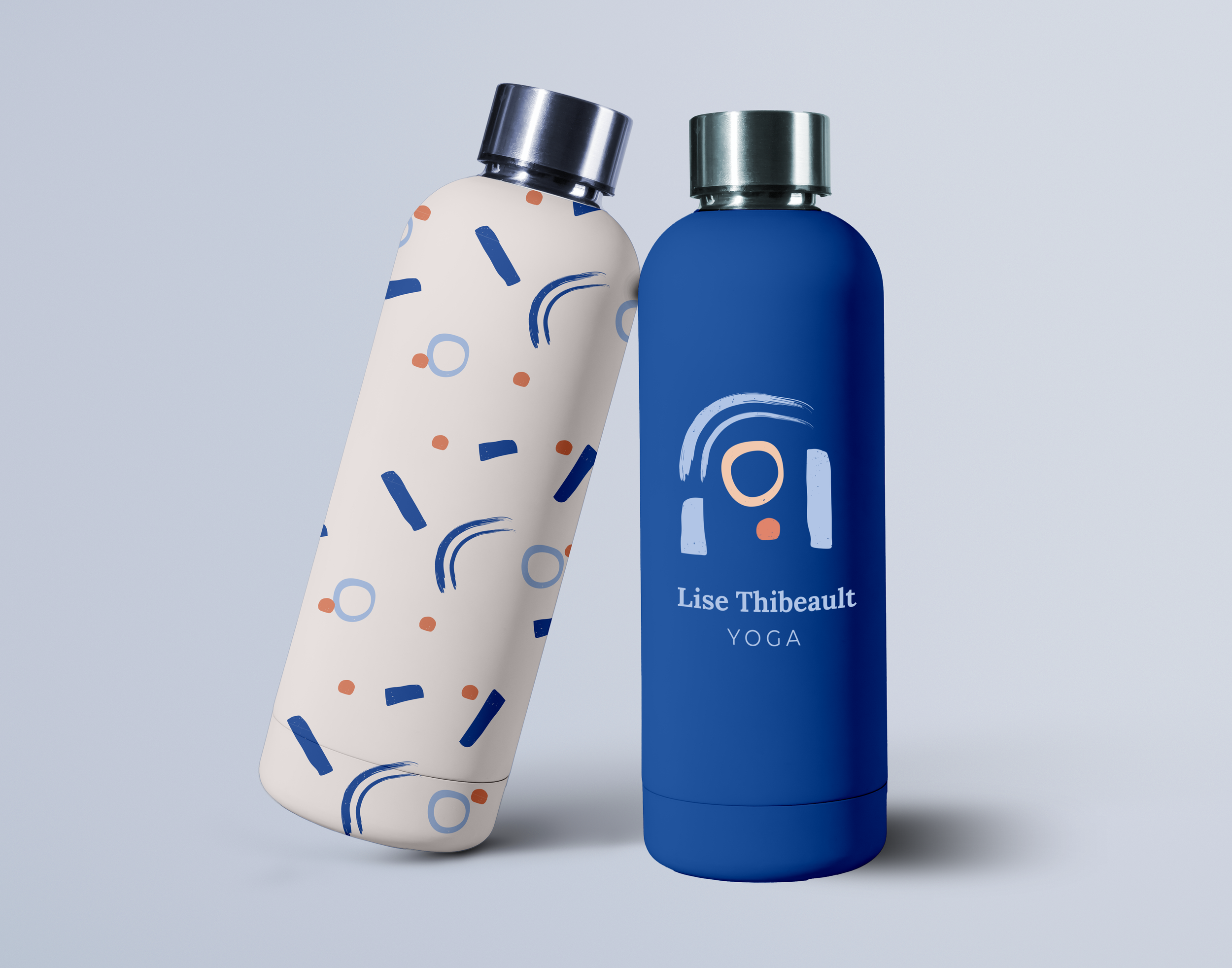 Deux bouteilles de lotion ou de parfum avec des capuchons métalliques, une blanche à motifs abstraits bleus et orangés, une bleue avec une inscription "Lise Thibeault Yoga".