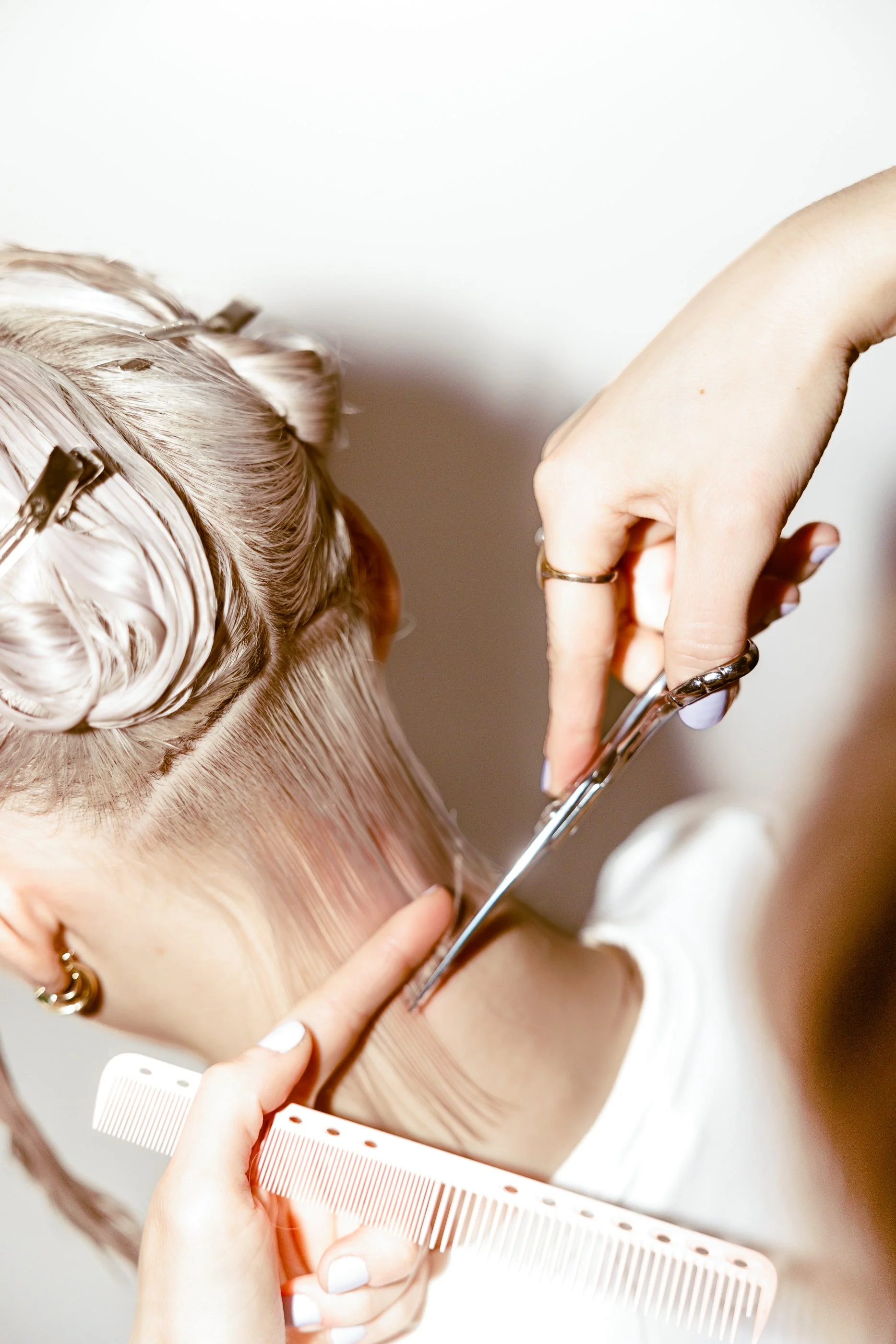 Hair stylist cutting a client's blonde hair with scissors during a haircut or styling session at the Paloma hair salon in Jersey City.