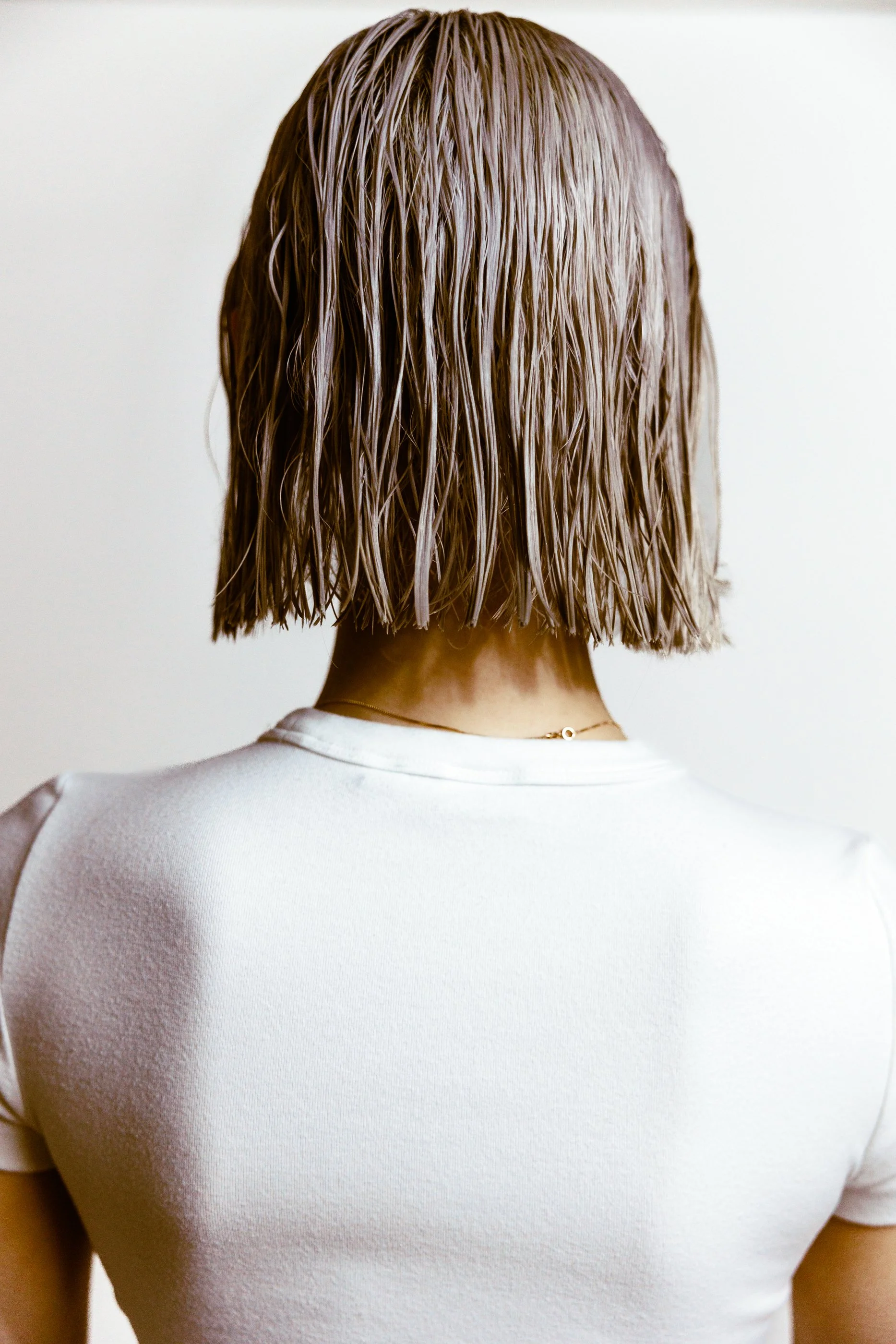 Back view of a person with wet, chin-length blonde hair at the hair salon in Jersey City.