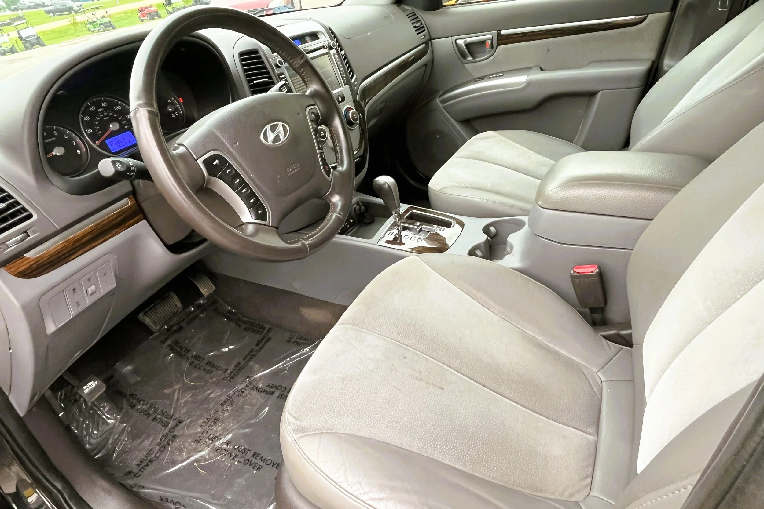 Interior of a Hyundai vehicle showing the steering wheel, dashboard, front seats, and center console with an automatic transmission shifter.