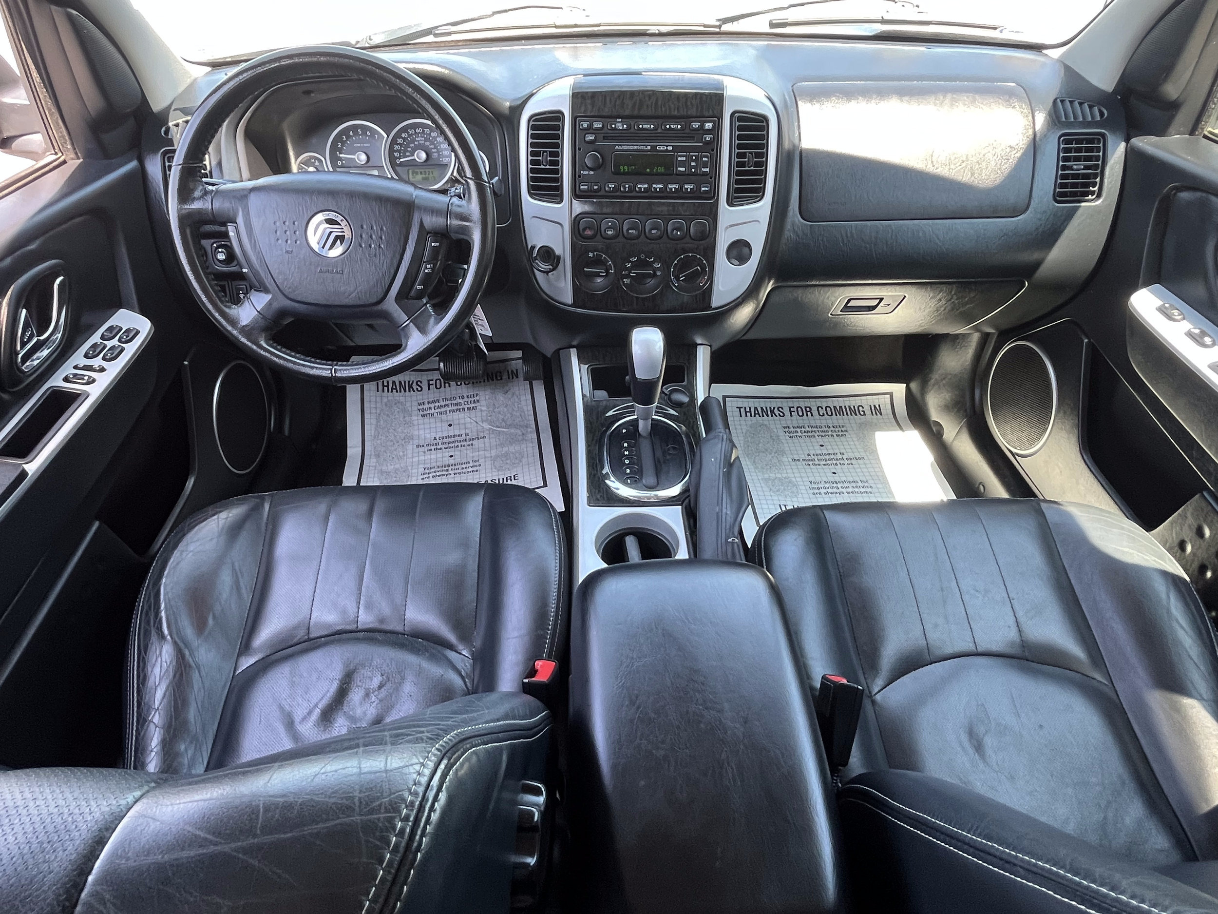 Interior of a vehicle showing the dashboard, steering wheel, center console with gear shift, and front seats with black leather upholstery.