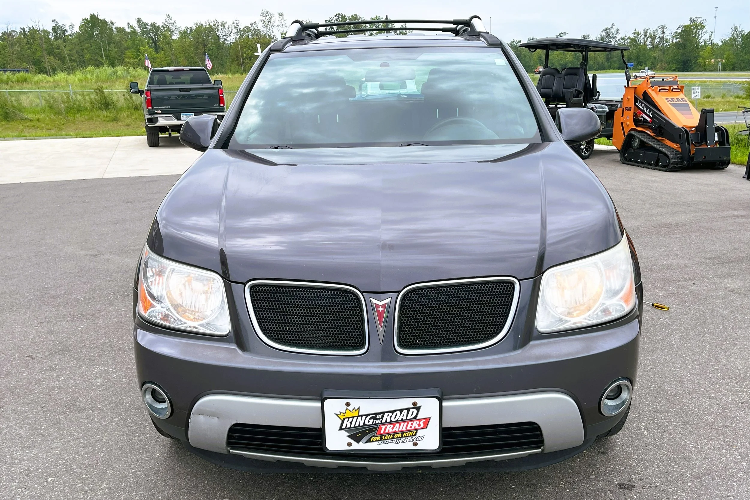 Black Pontiac SUV parked on a paved lot with other vehicles and landscaping in the background.