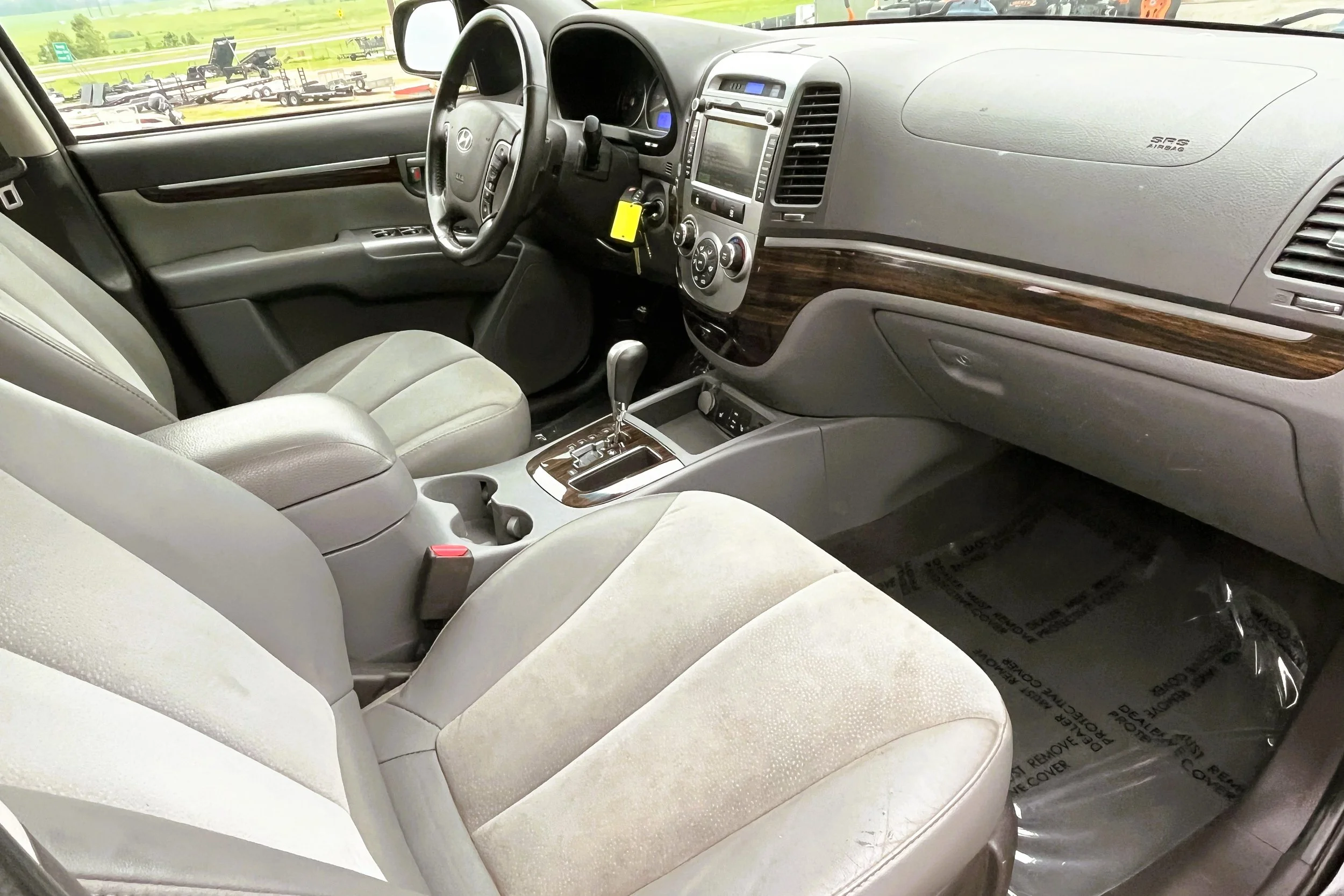 Interior of a beige car showing front seats, dashboard, steering wheel, and center console with gear shift.