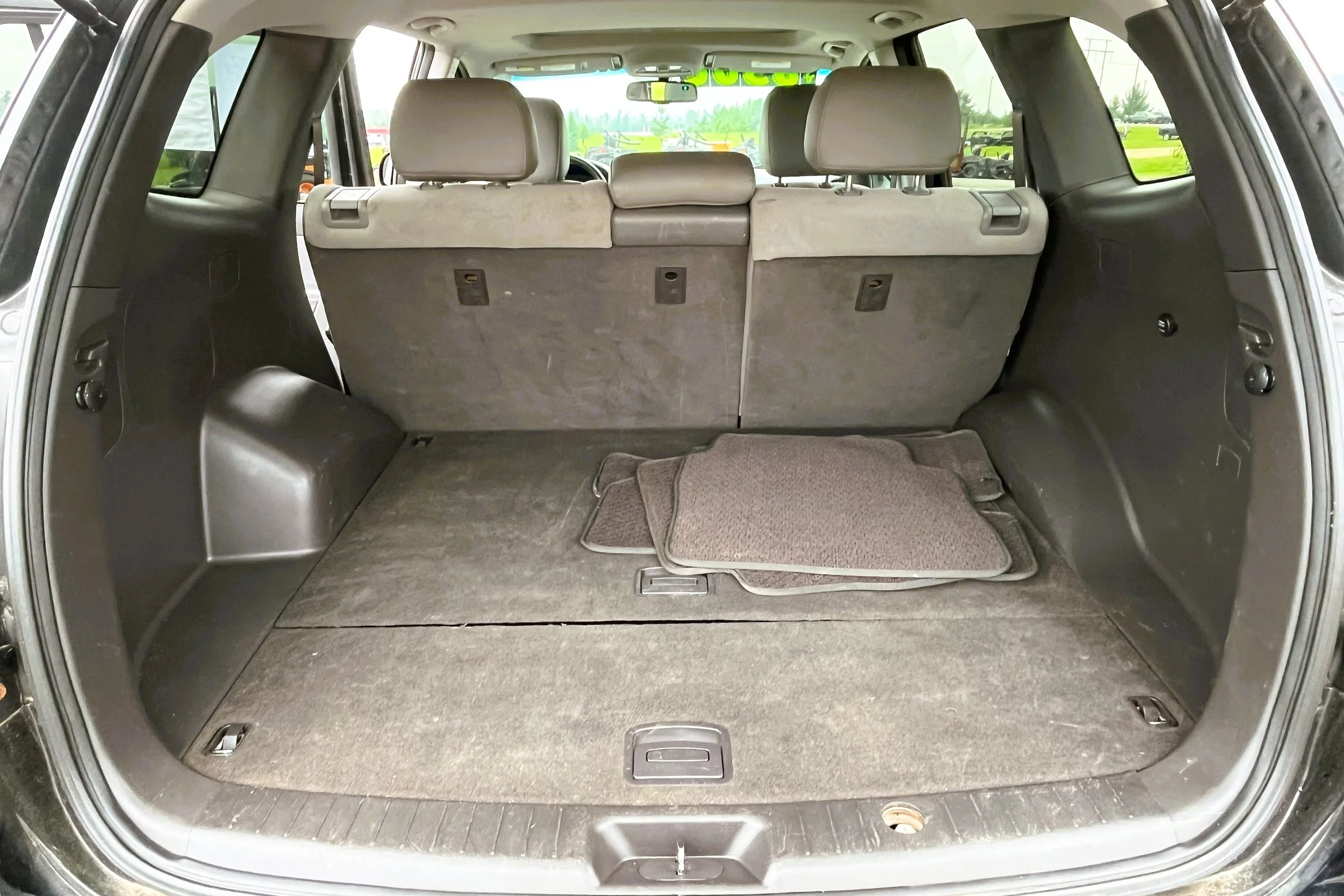 The interior of an SUV's cargo area with folded third-row seats and a set of gray floor mats.