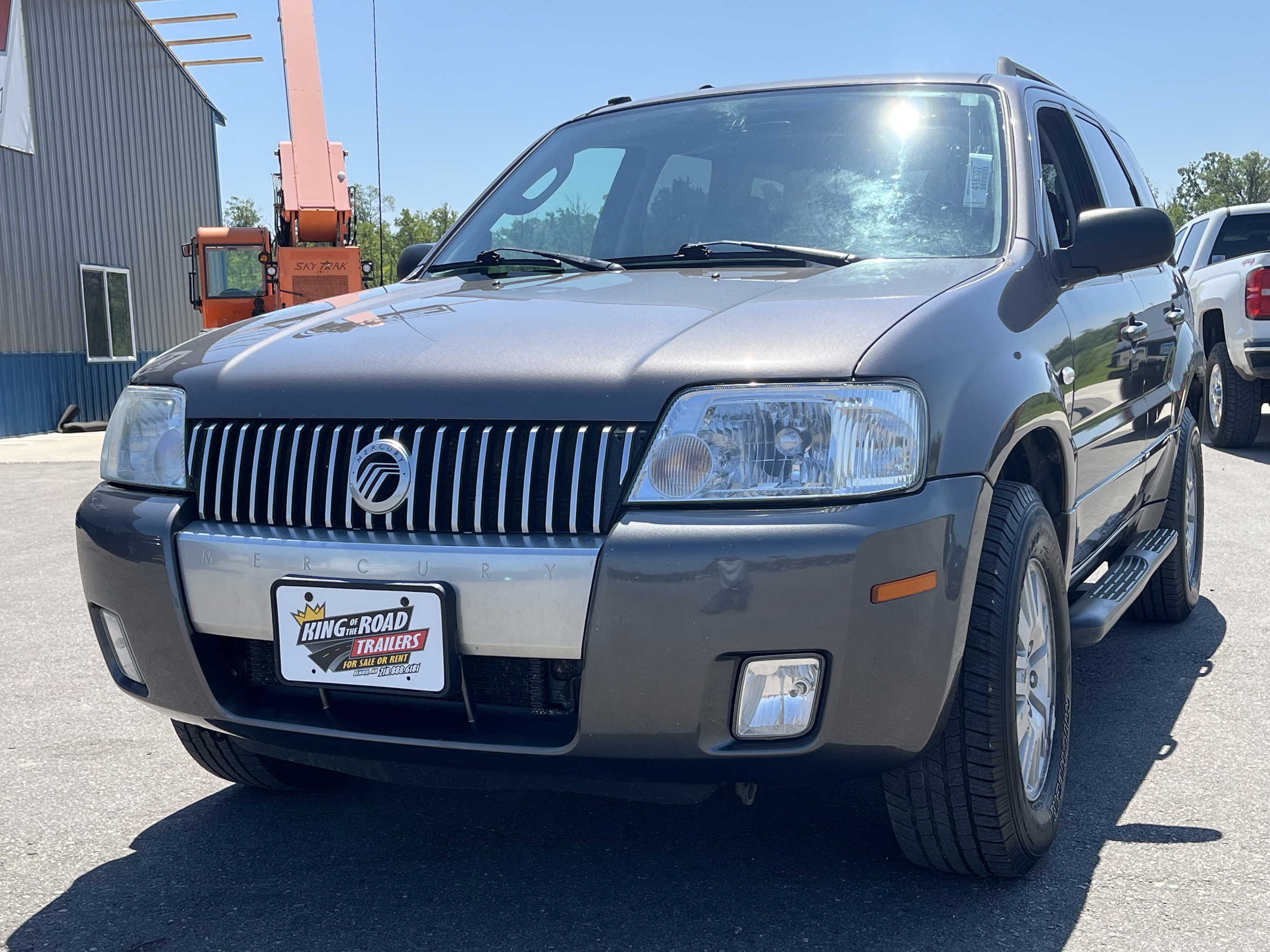 Gray Mercury SUV parked outdoors with a black and chrome front grille, clear headlights, and black side mirrors, on a sunny day at a dealership lot.