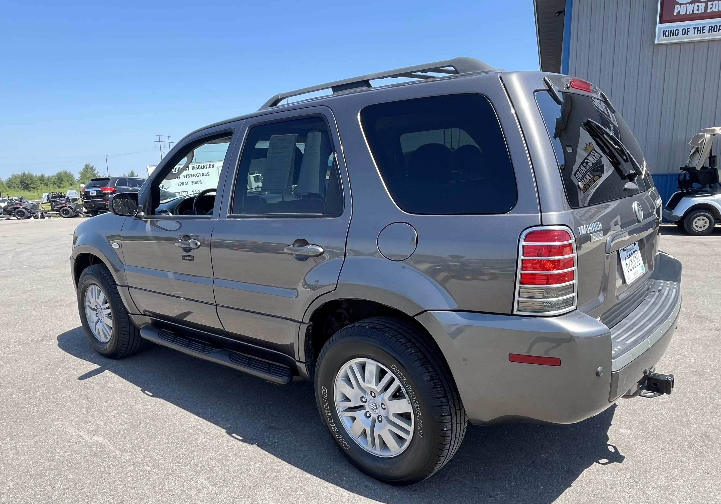 Gray SUV parked in lot with other vehicles and a large building in the background.