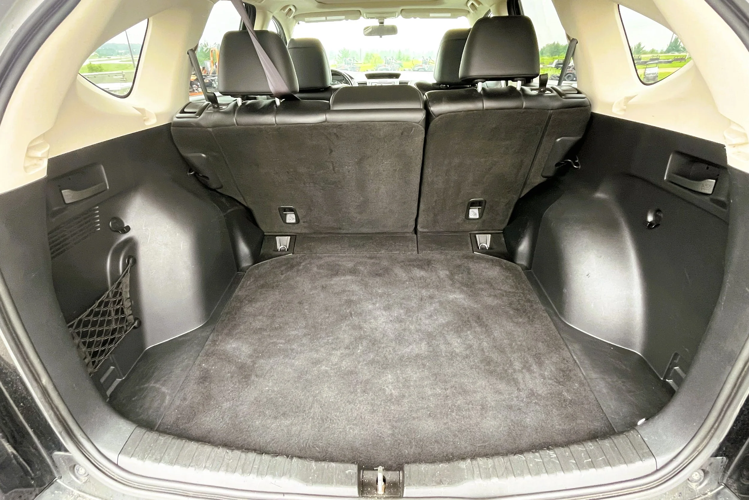 Interior of an SUV cargo area with folded-down back seats and a black carpeted floor.