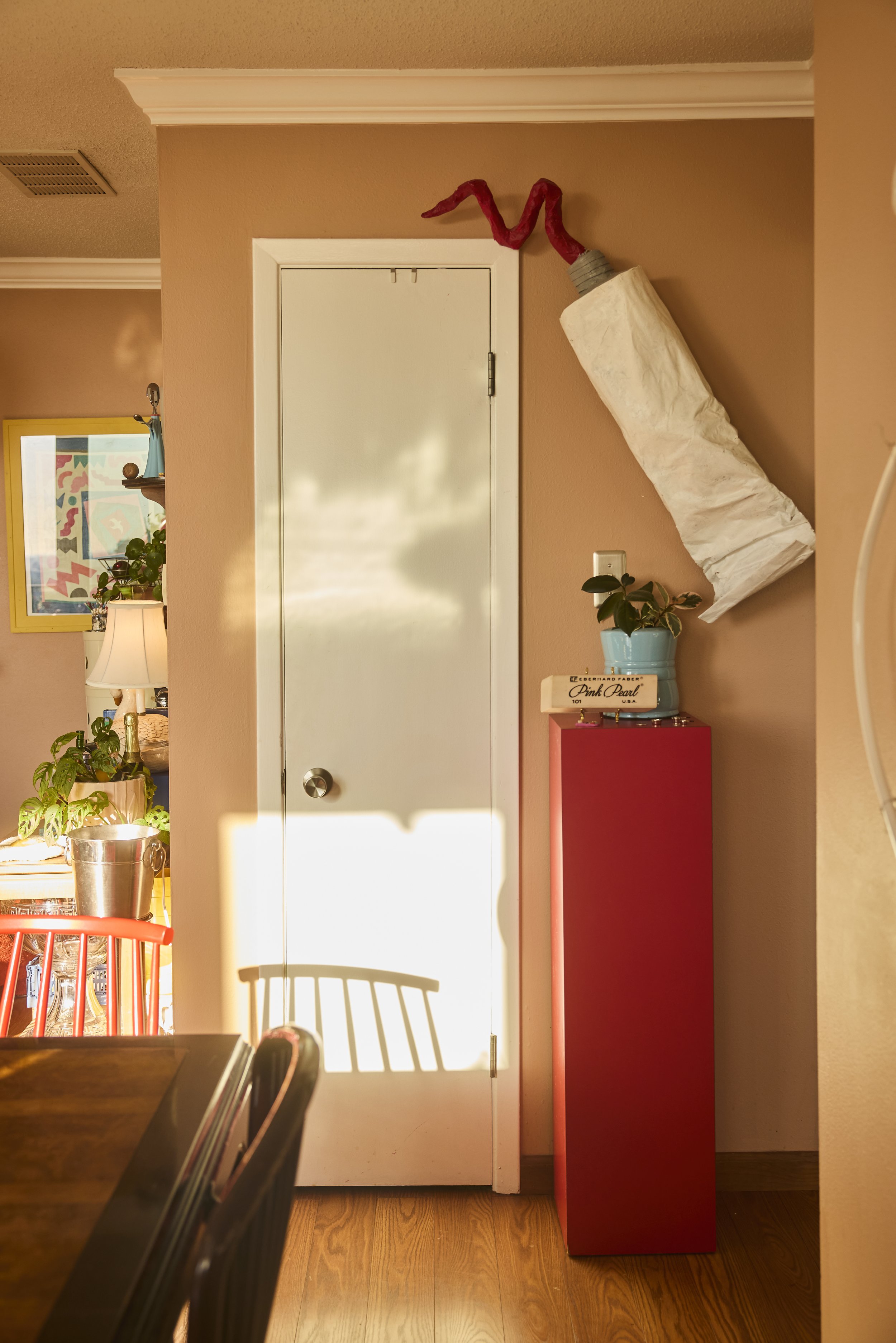 View from the dining room showcases a large paint tube on the wall in Zach and Taylor's Houston, TX apartment. Image by Austin-based lifestyle photographer, Mackenzie Smith.