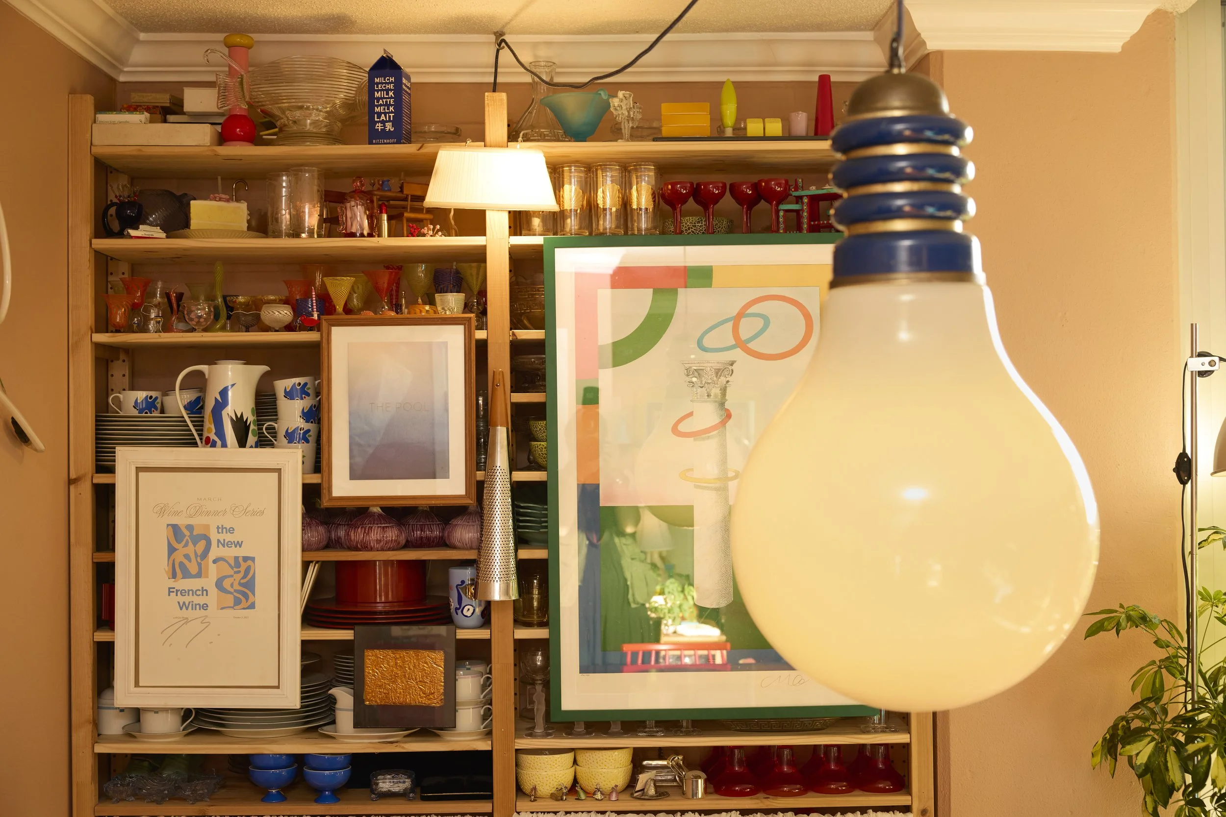 Open shelving holds all the kitchenware in Zach and Taylor's Houston, TX apartment, complete with kitschy artwork and hanging light bulbs. Image by Austin-based lifestyle photographer, Mackenzie Smith.