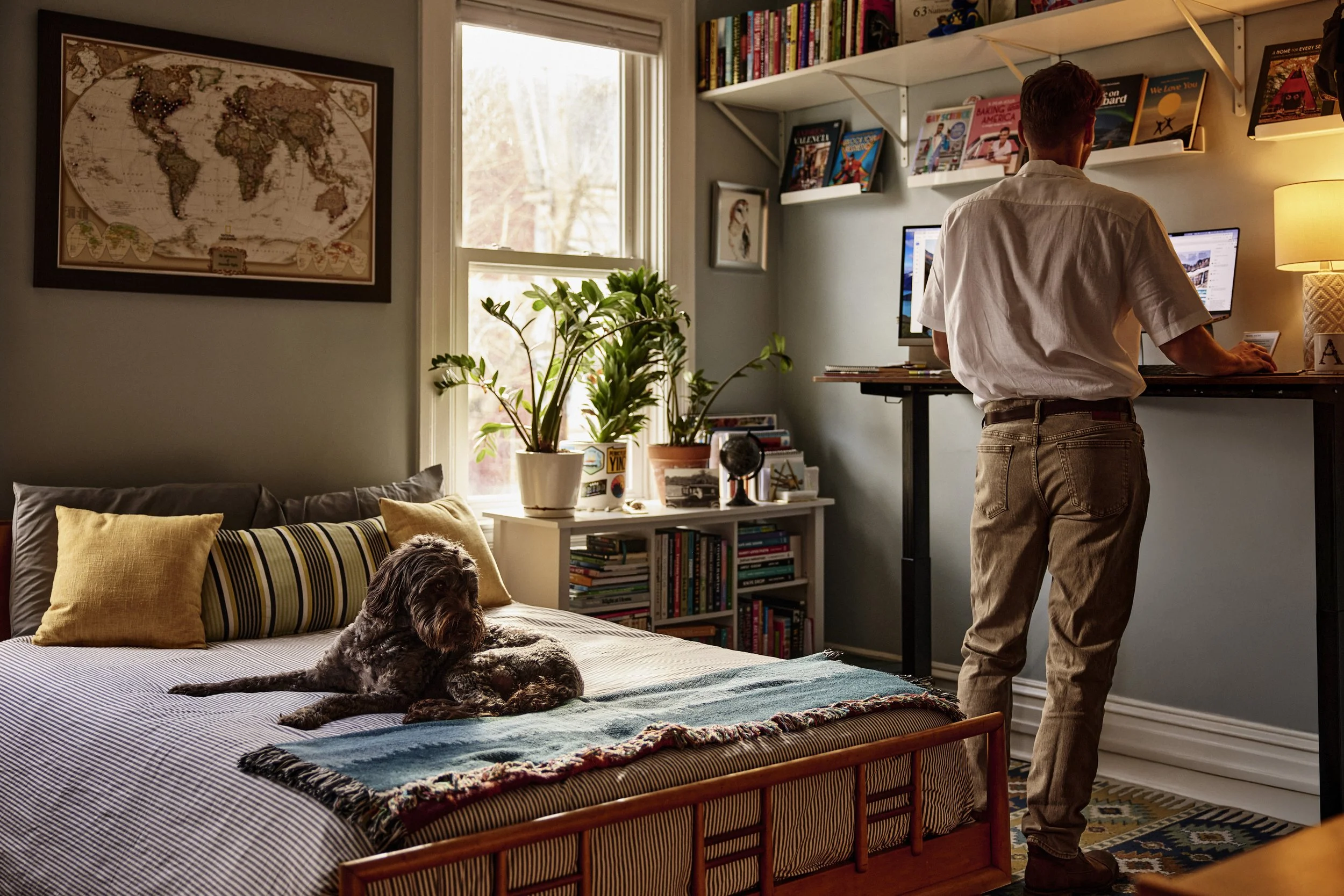 Alexander using his standing desk while his dog lounges on the bed. Image by Austin-based lifestyle photographer, Mackenzie Smith.