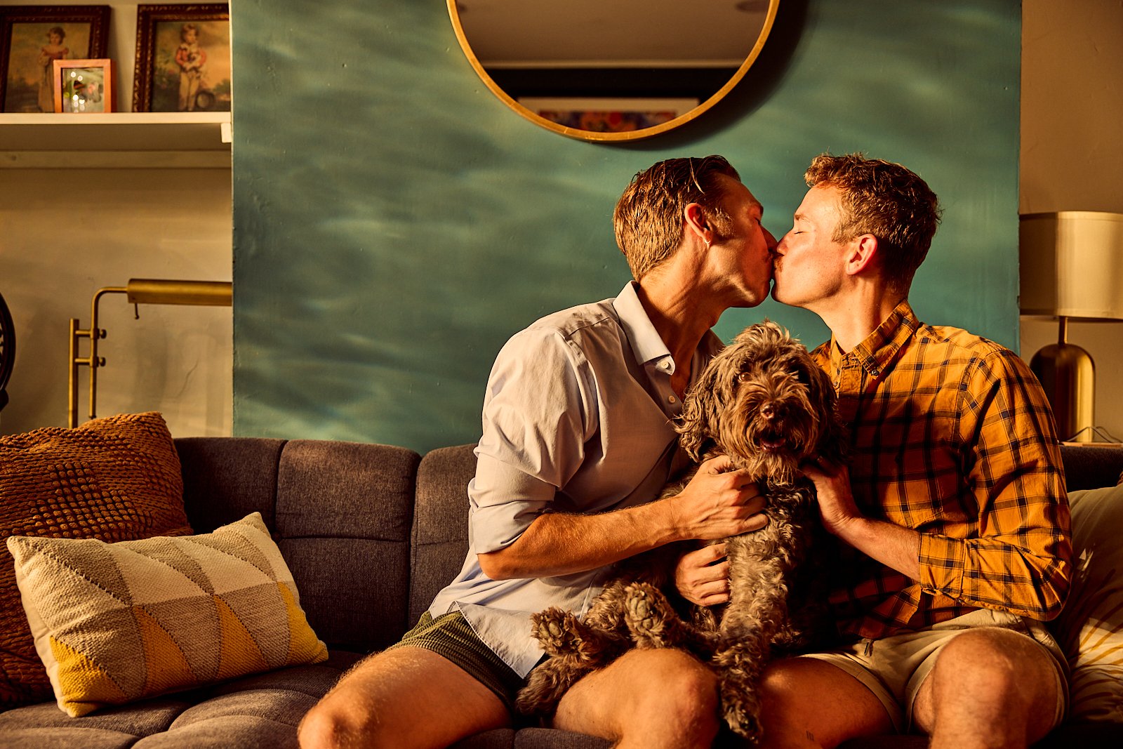 Alexander, Bobby, and their dog kissing in the living room. Image by Austin-based lifestyle photographer, Mackenzie Smith.