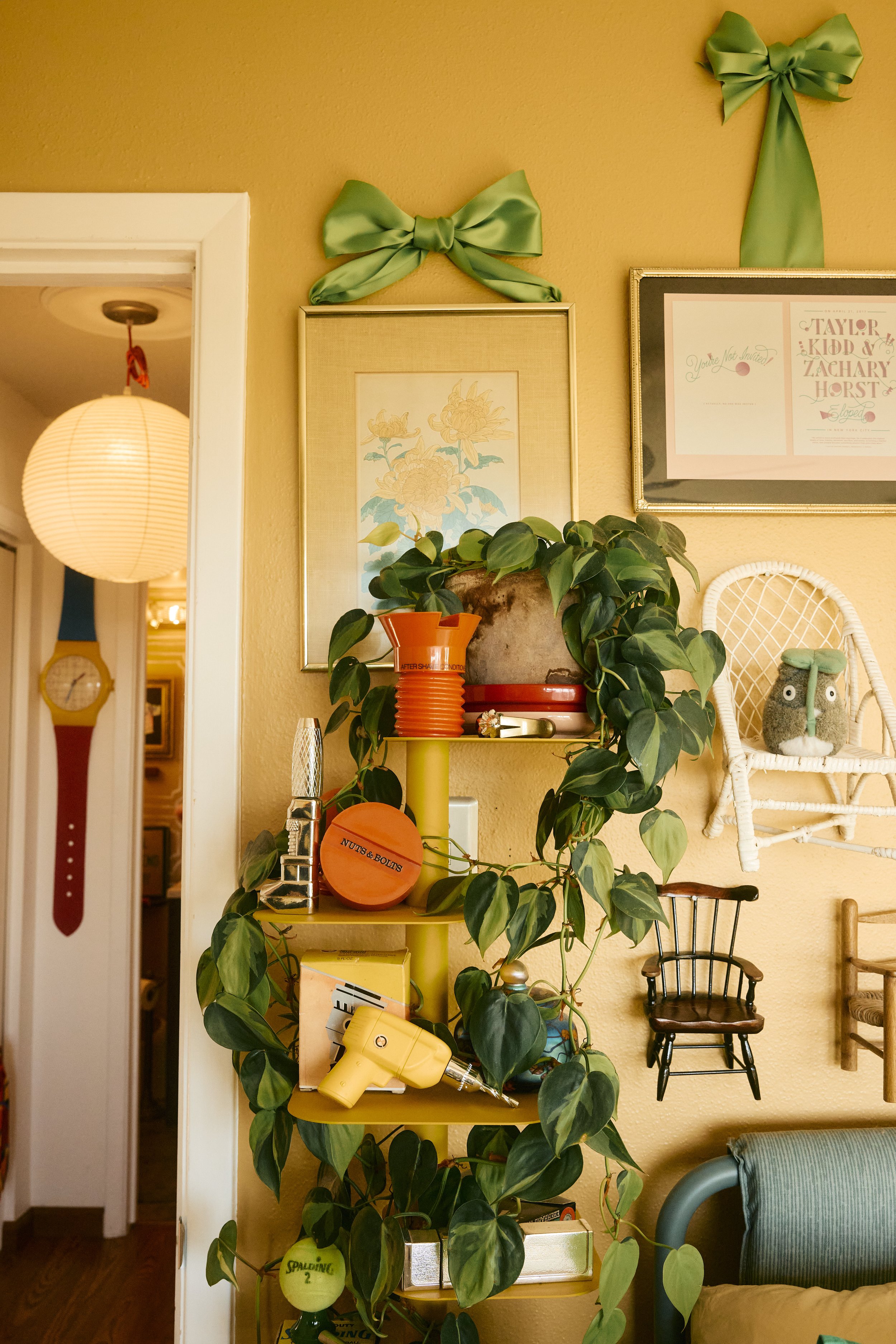 Green house plants, a giant watch and green silk bows on the walls of Zach and Taylor's eclectic Houston, TX apartment. Image by Austin-based lifestyle photographer, Mackenzie Smith.