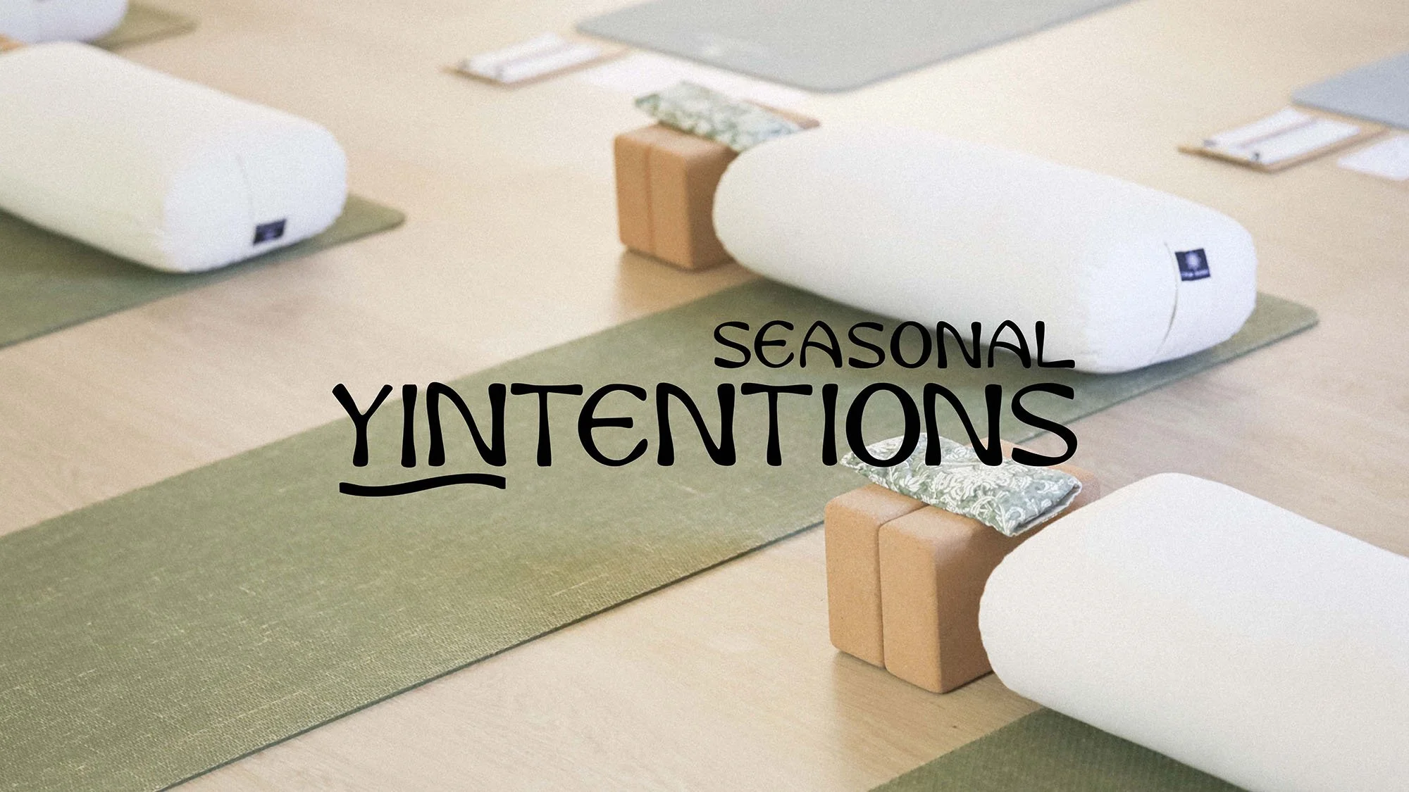 Yoga mats, bolsters, and blocks arranged on the floor with text reading 'Seasonal Yintentions'.