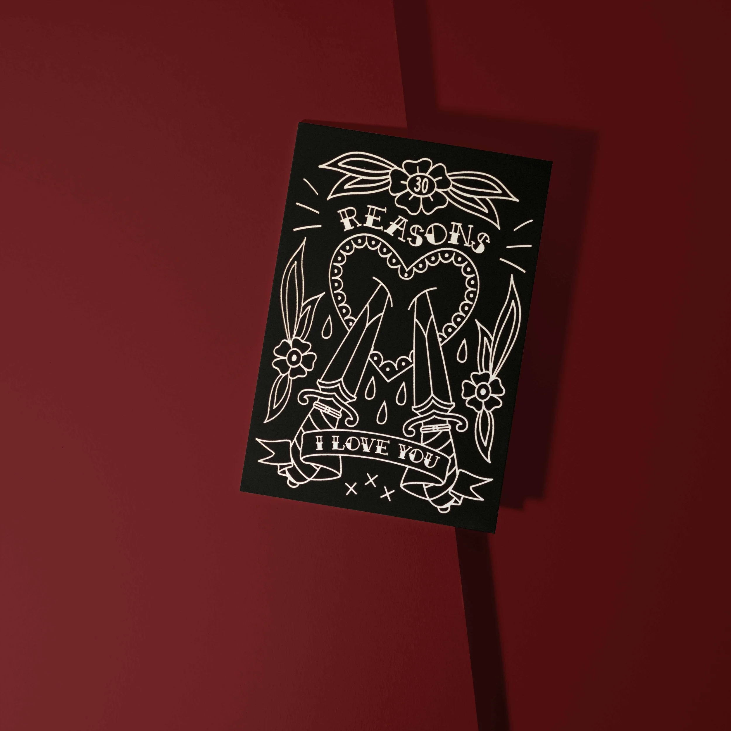 A black card with white line artwork of a heart, two swords, flowers, and a banner that reads "30 Reasons I Love You". 