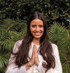 Dark haired woman smilling with hands in prayer at her chest