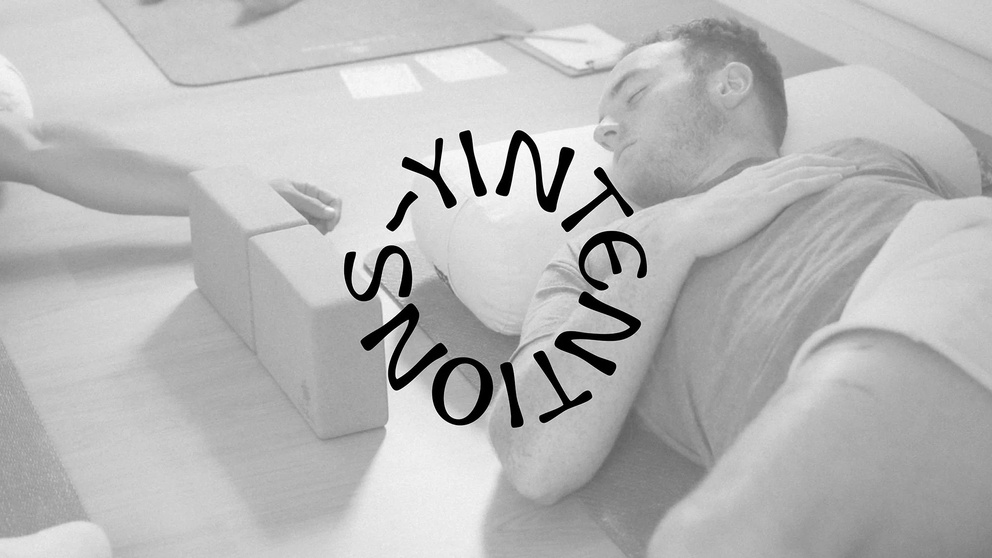 A man stretching in a yoga class on the floor with a text overlay saying "YINTENTIONS".