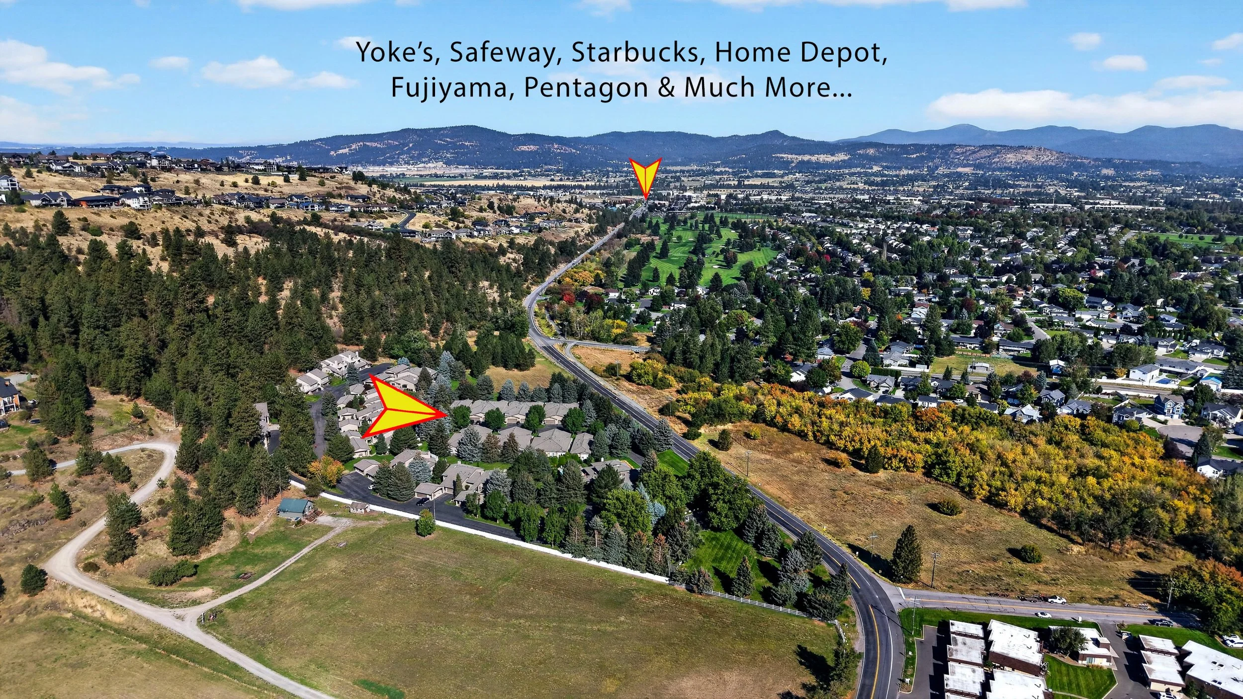 An aerial view of a suburban residential neighborhood with houses, trees, roads, and patches of farmland, with hills and mountains in the background. There are two red and yellow arrows pointing to specific areas in the image.