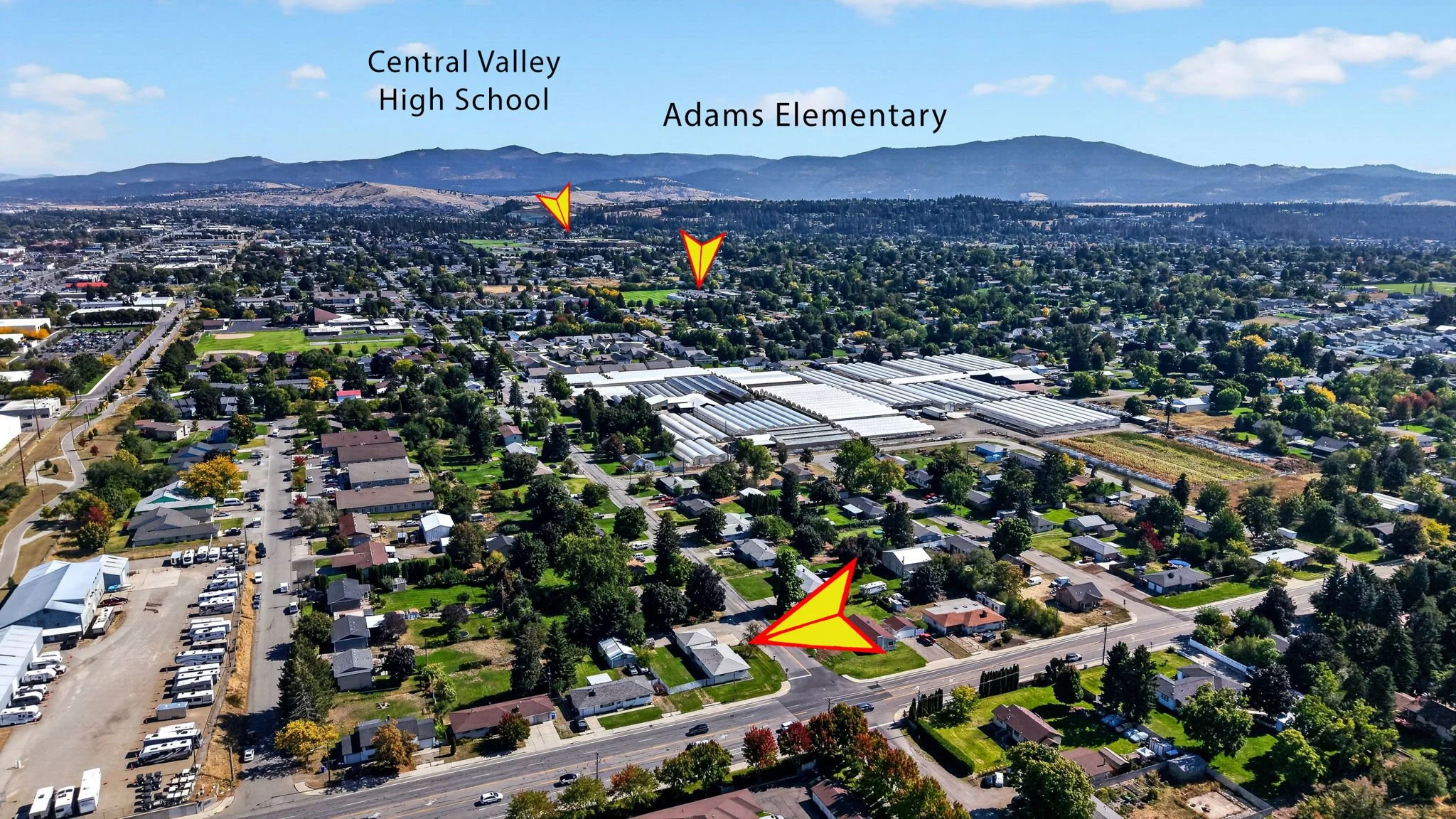 An aerial view of a suburban area with various houses, streets, and green spaces, with mountains in the background. Labels indicate Central Valley High School and Adams Elementary, with a red and yellow arrow pointing to a house in the foreground.