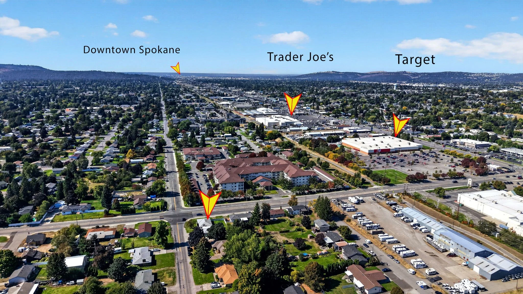 Aerial view of Spokane with labels pointing out Downtown Spokane, Trader Joe's, and Target, showing residential neighborhoods, commercial areas, and parking lots under a partly cloudy sky.