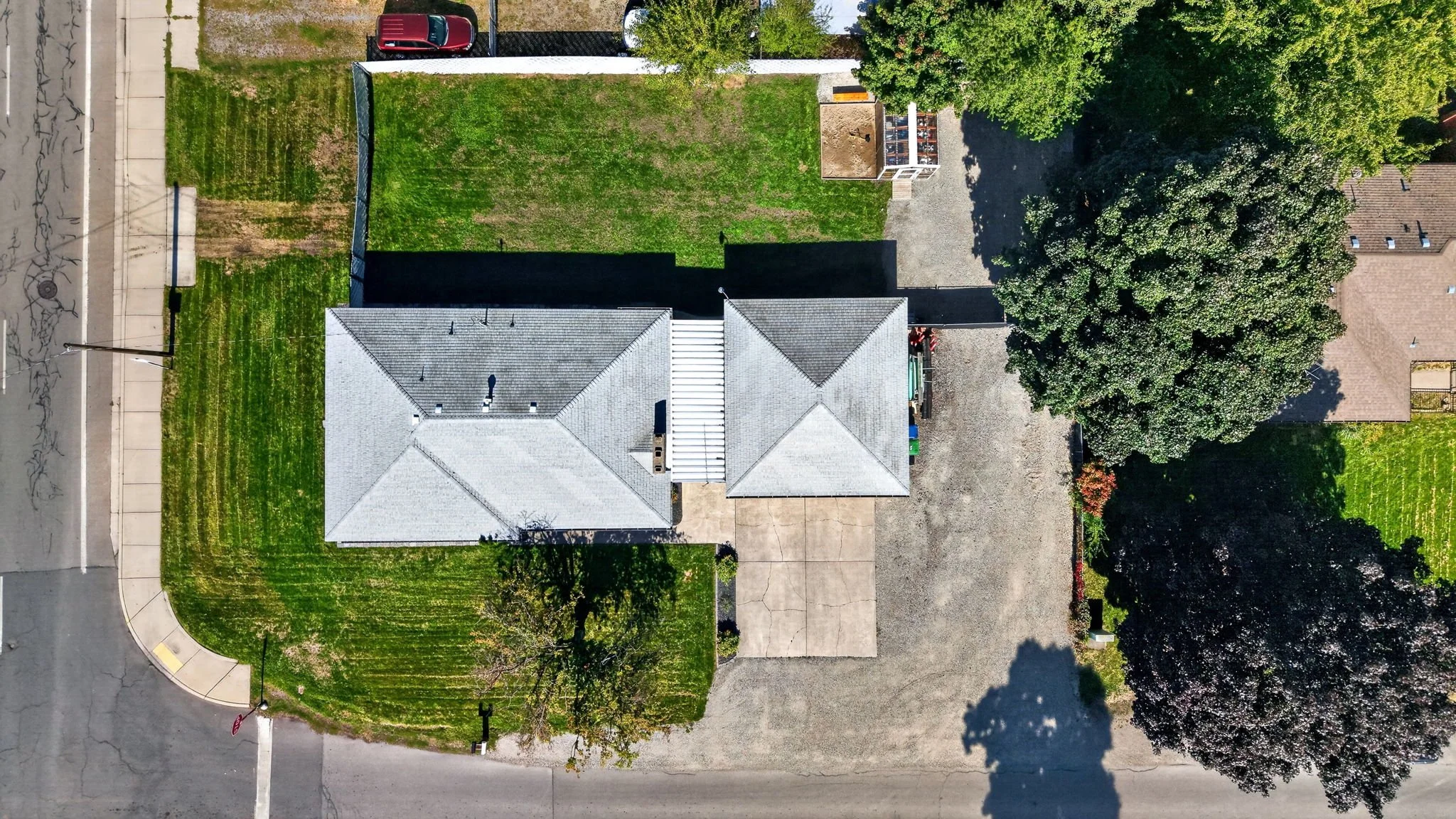 An aerial view of a residential backyard with a house, trees, grass, and a driveway.