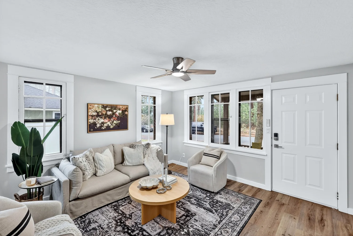 Bright living room with a beige sofa, round wood coffee table and large windows