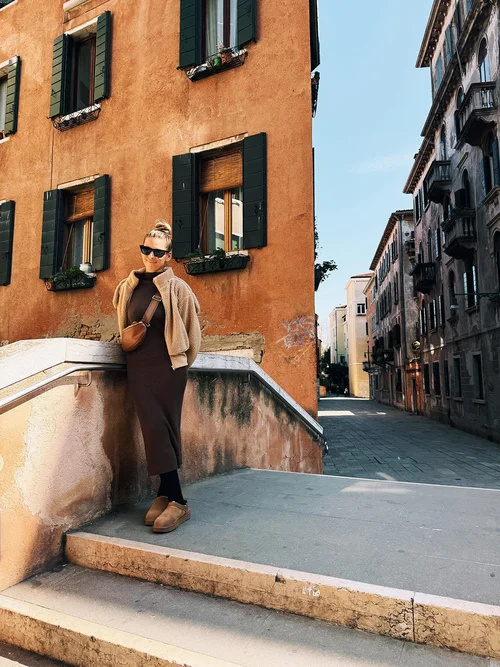 Courtney leaning on a stone bridge railing in Venice