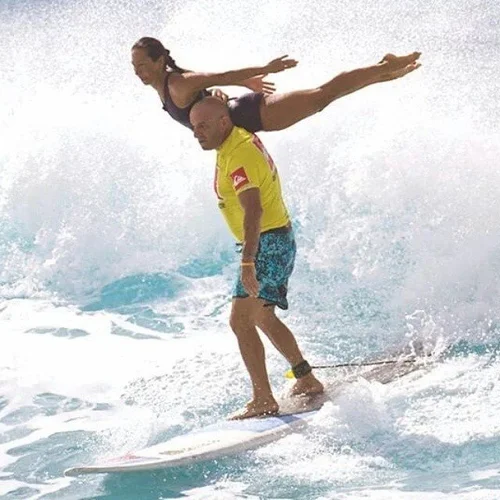 Stephanie in an overhead split lift tandem surfing at Mākaha