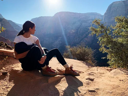 Tricia resting on a sandstone ledge above a canyon
