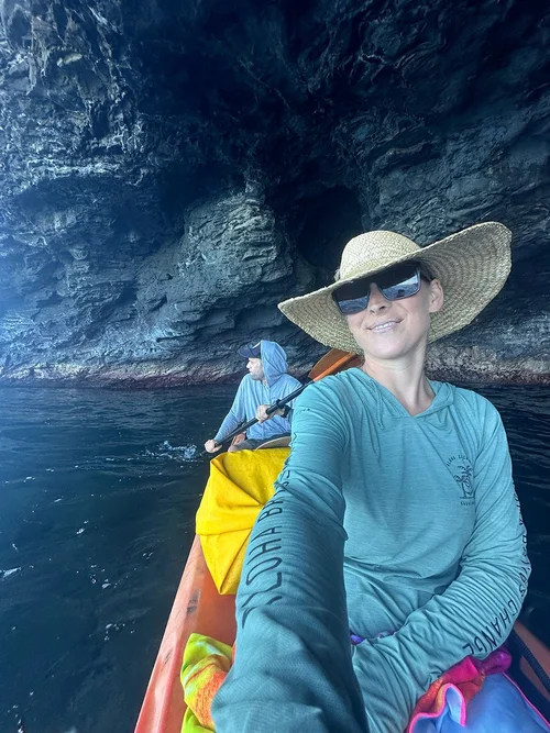 Courtney kayaking into a sea cave along the Kauaʻi coast